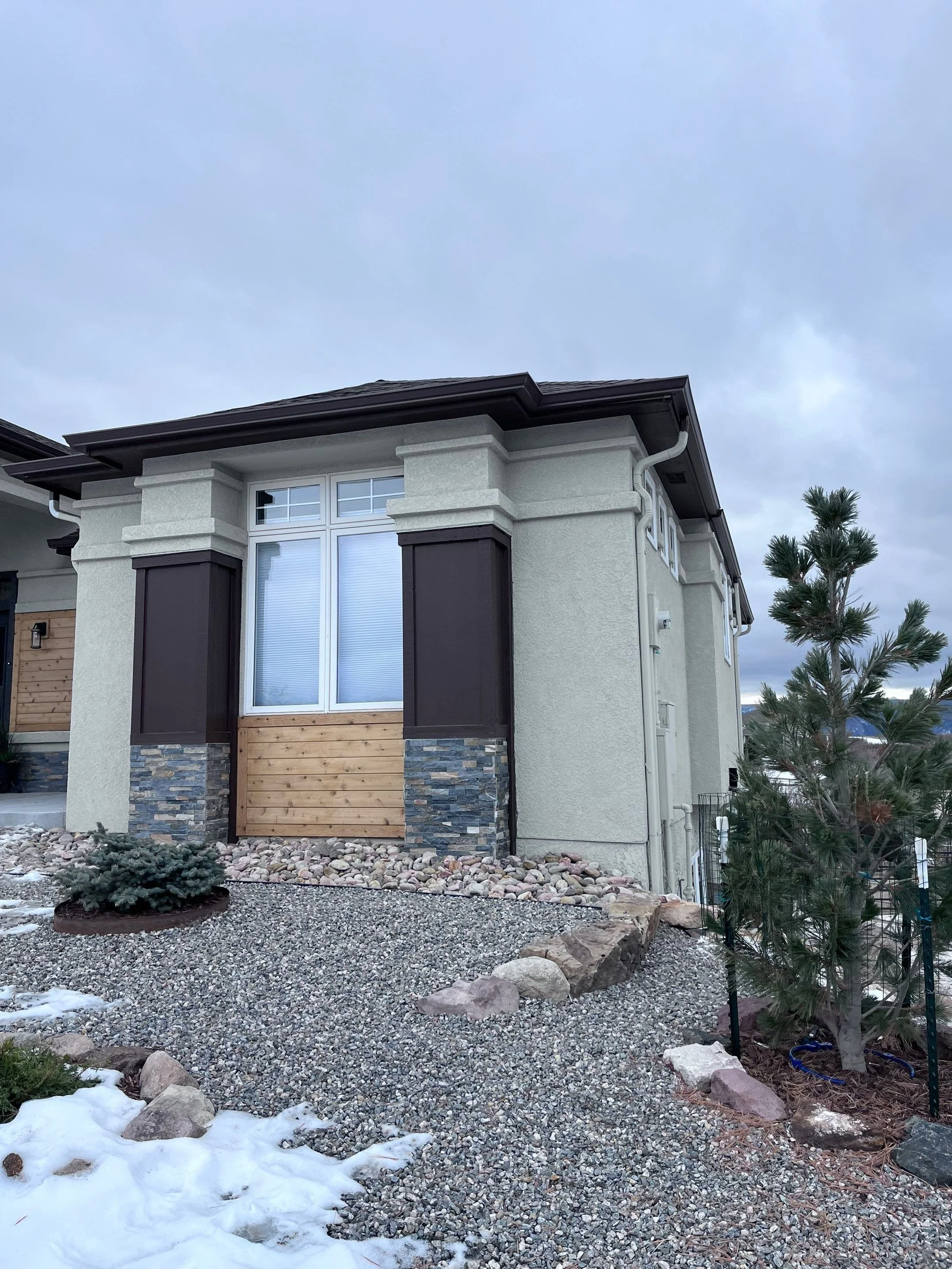 Modern gray home with dark seamless gutters and downspouts installed along the roofline.