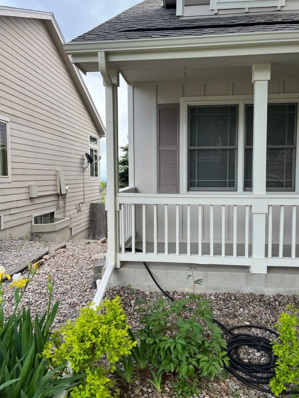 New seamless gutters and downspouts installed around a covered front porch and lower roof section.