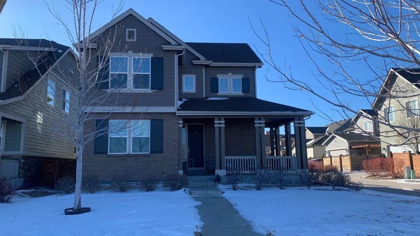 Two-story home with white seamless gutters and downspouts after a winter snowfall.