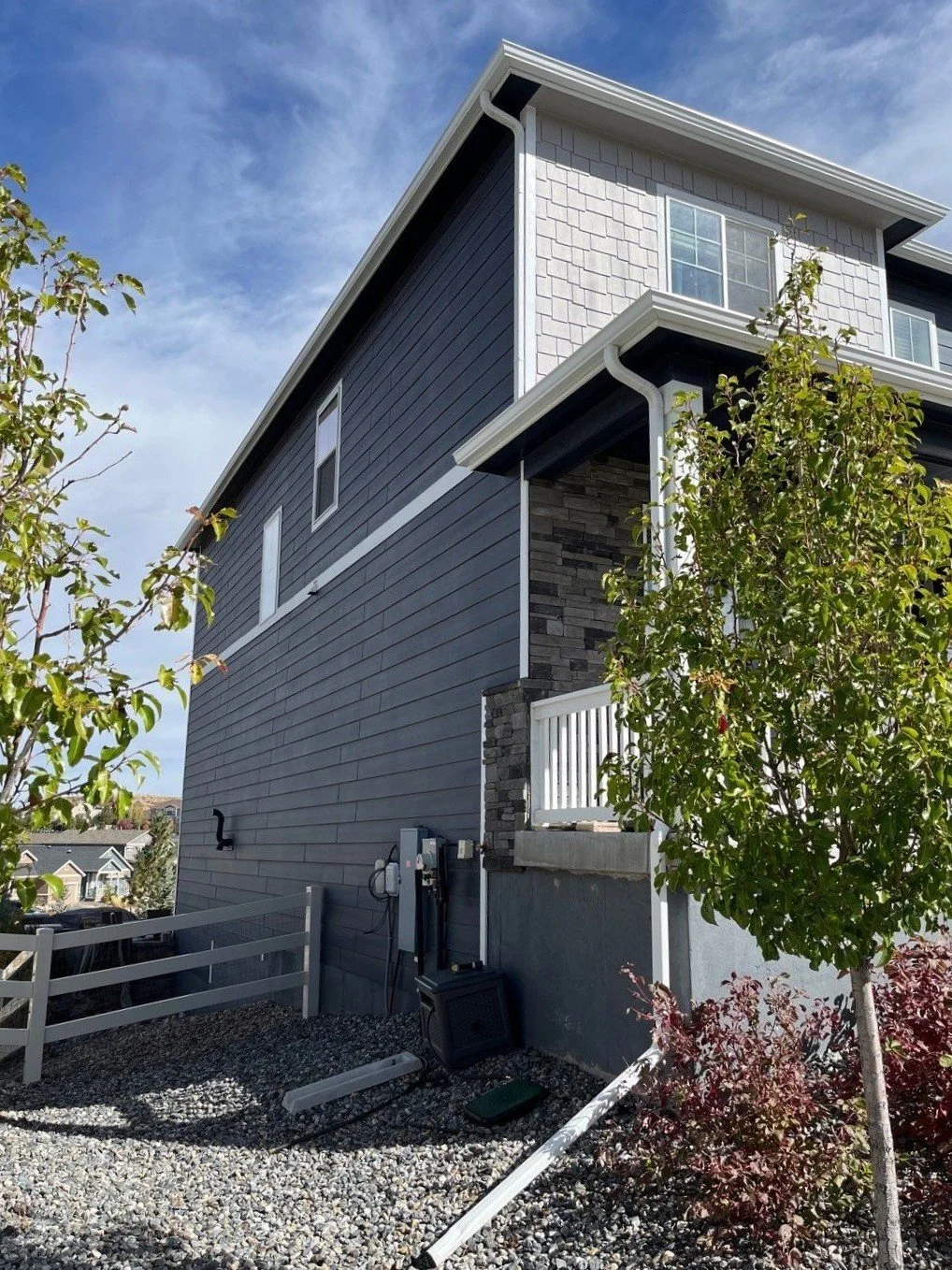 Front porch of a dark blue home with white seamless gutters and downspouts.