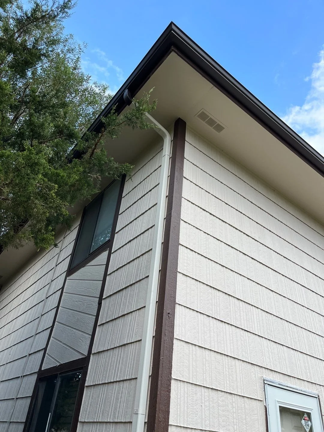 Custom seamless gutters installed along the side roof edge of a light-colored home.
