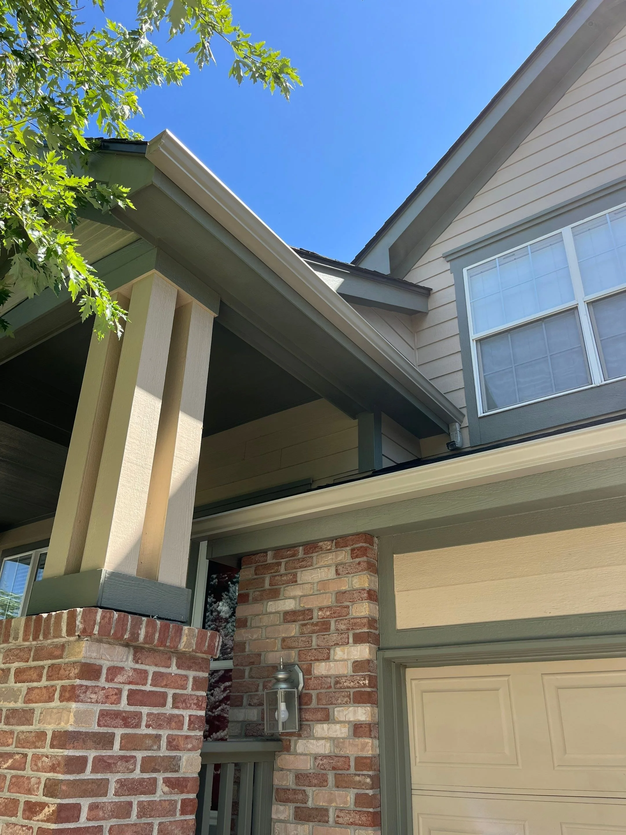 Residential gutter replacement completed above the garage and covered entry of a brick-and-siding home.