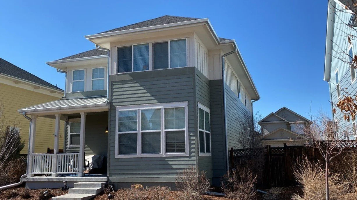 Multi-story home with a seamless gutter system and downspouts installed around the upper rooflines.