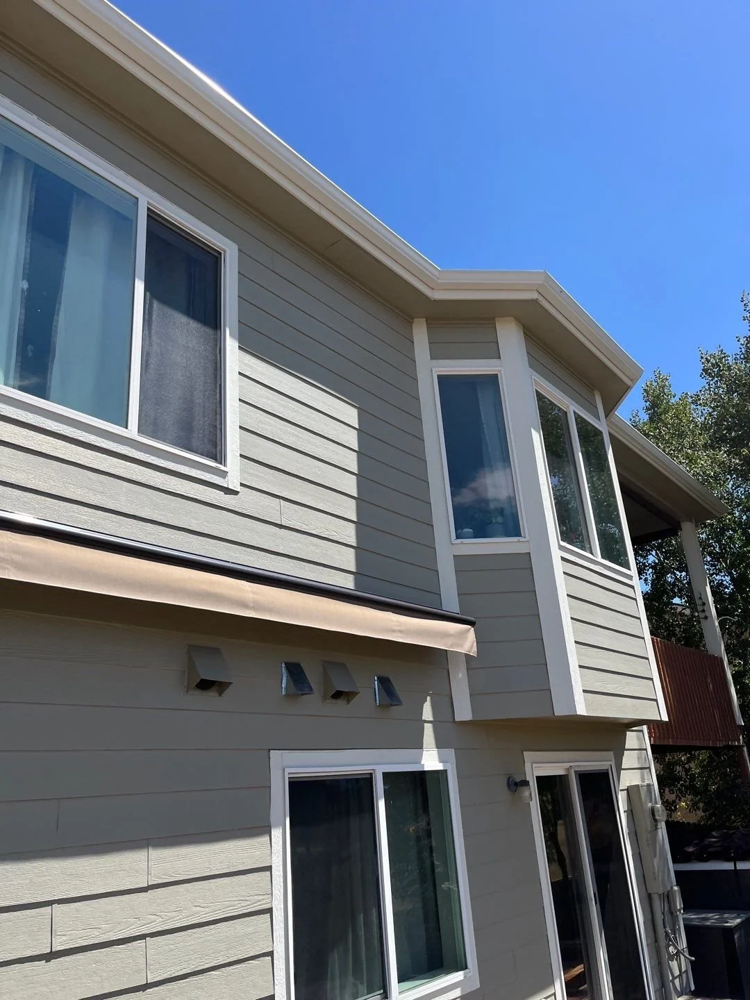 New gutters and downspouts installed across the back roofline of a two-story home.