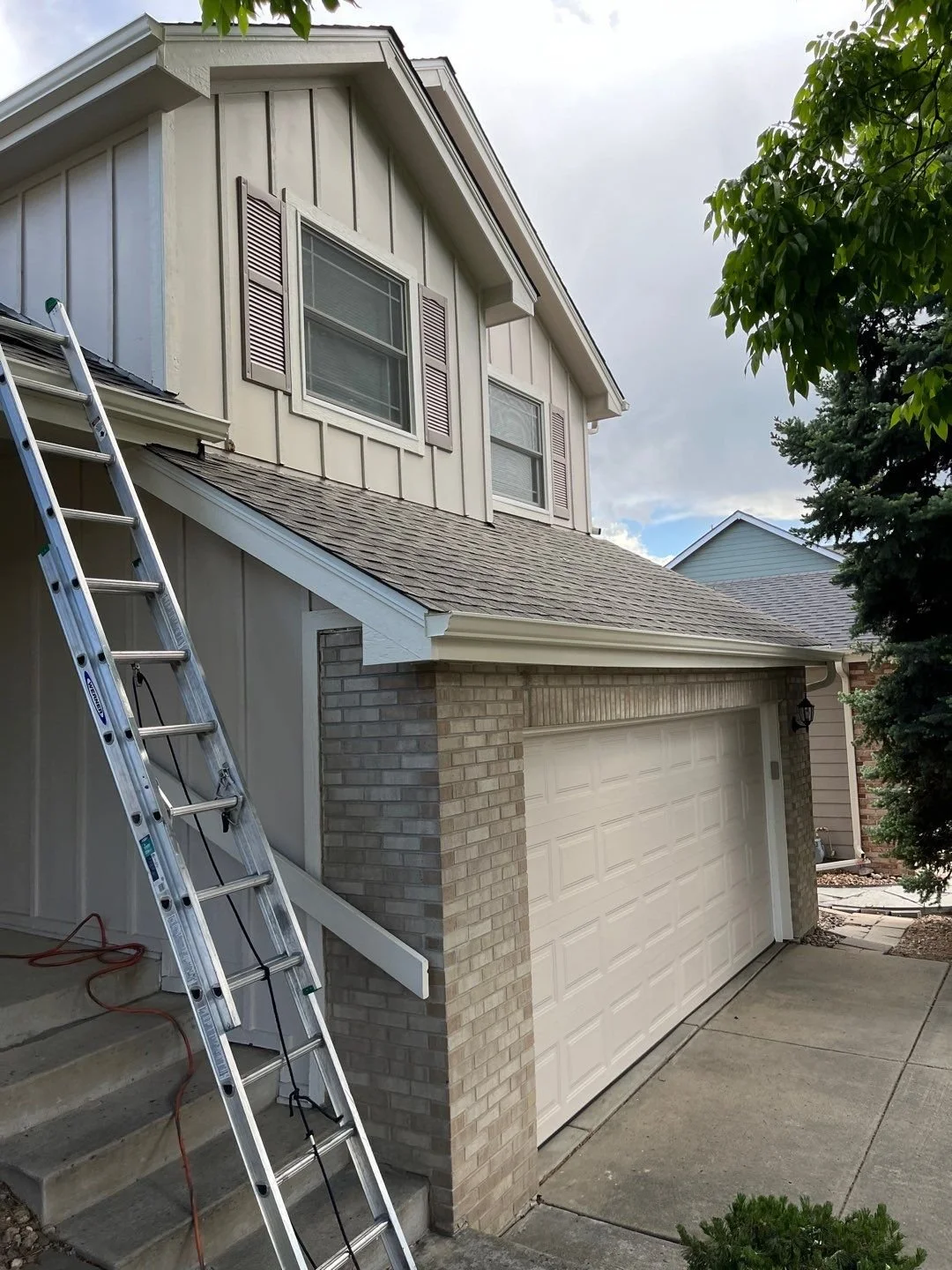 New linen-colored 5-inch seamless gutters being installed along the garage and front entry rooflines in Green Mountain, Lakewood.