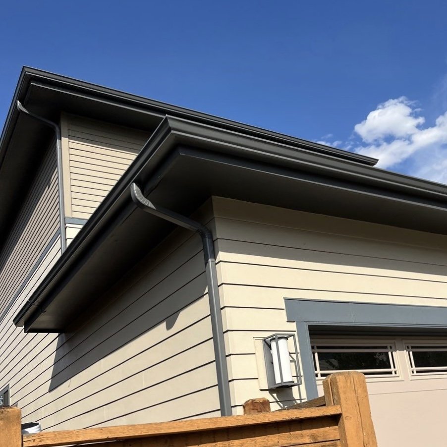Close-up of a completed seamless gutter and downspout replacement along a residential roofline.