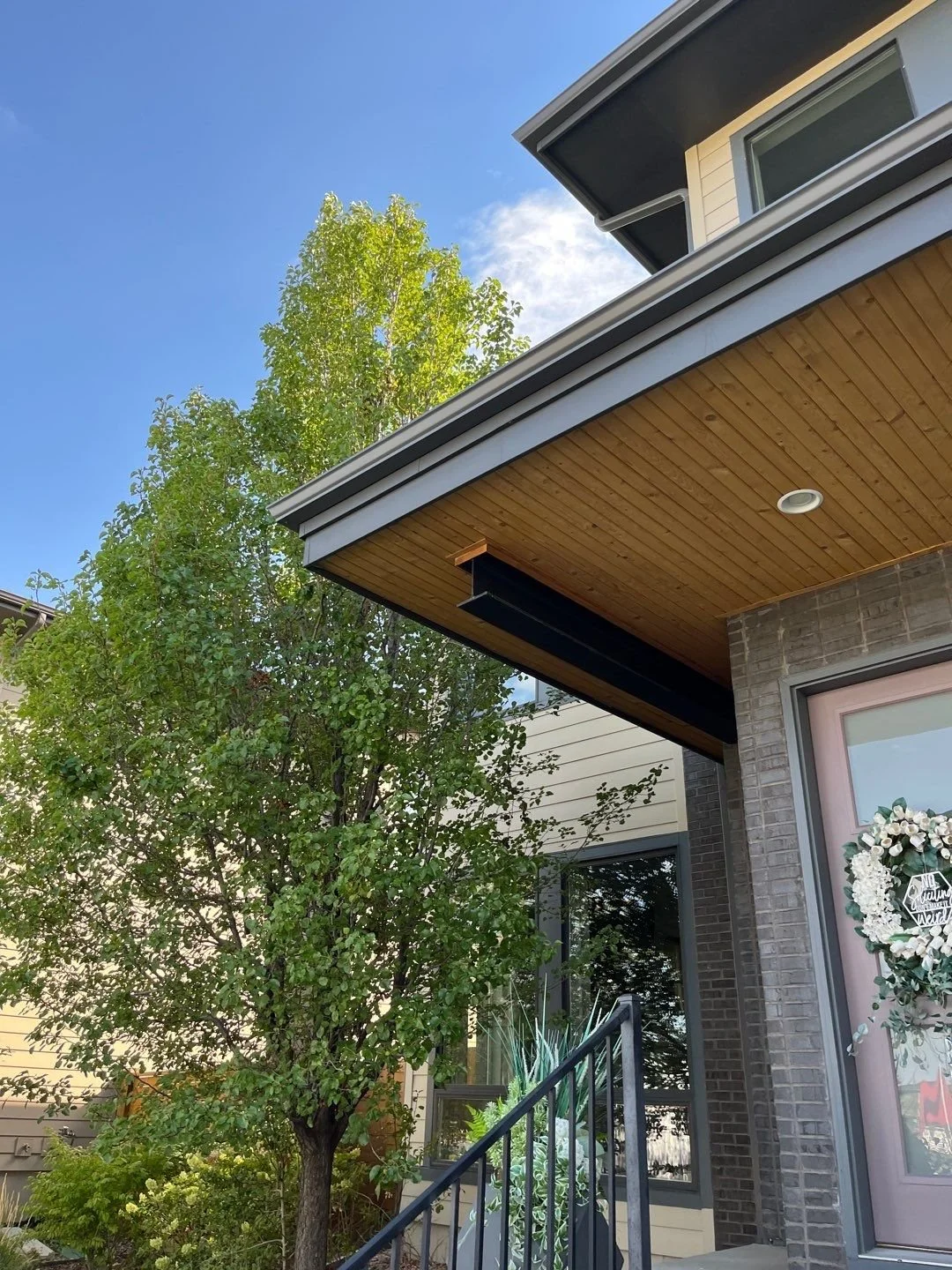 Close-up of a seamless gutter and downspout system beneath a deep roof overhang.