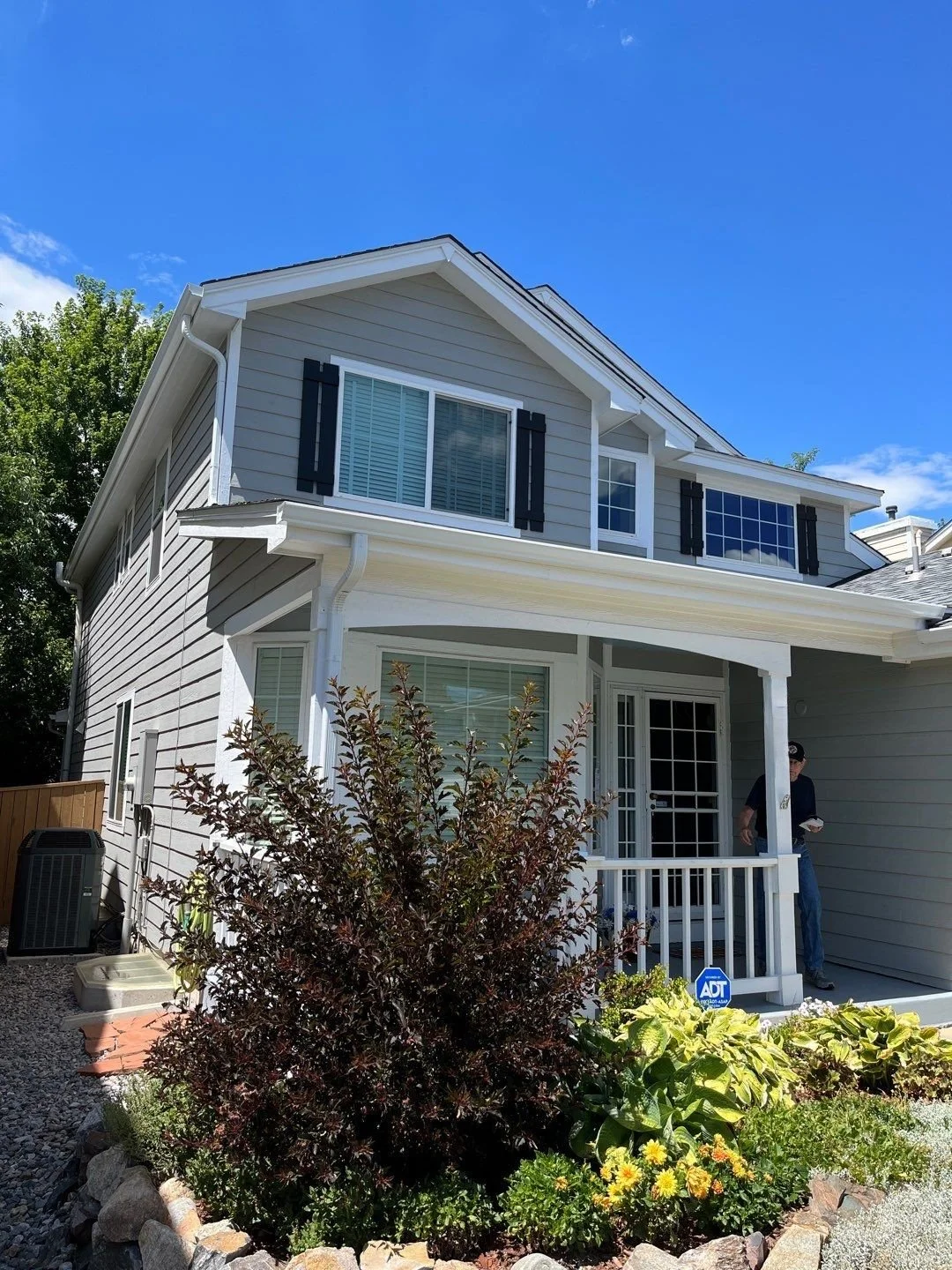 Seamless gutters and downspouts installed on a two-story home with a covered front porch.