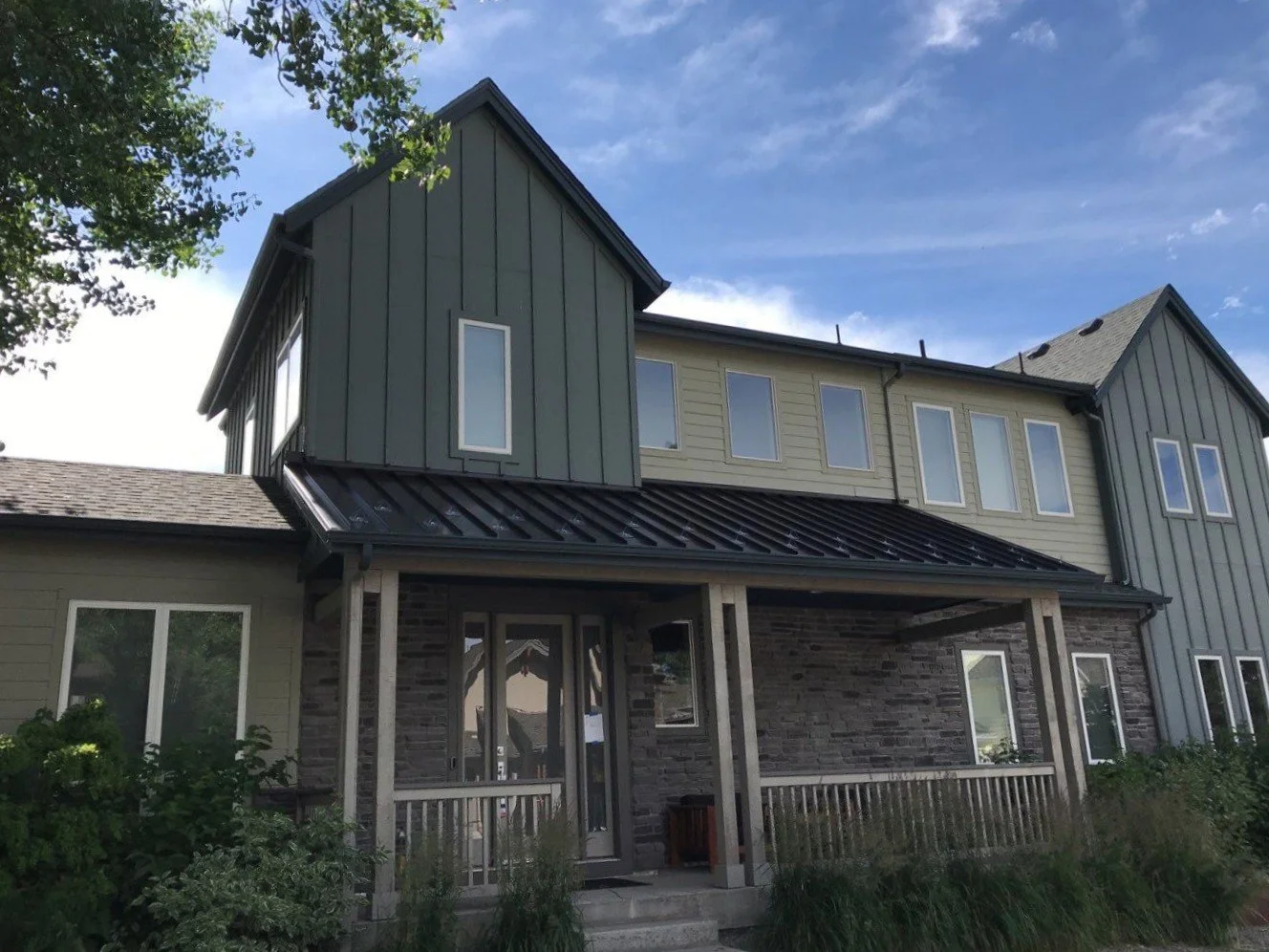 Custom seamless gutters and downspouts fitted around a covered porch and upper roof section.