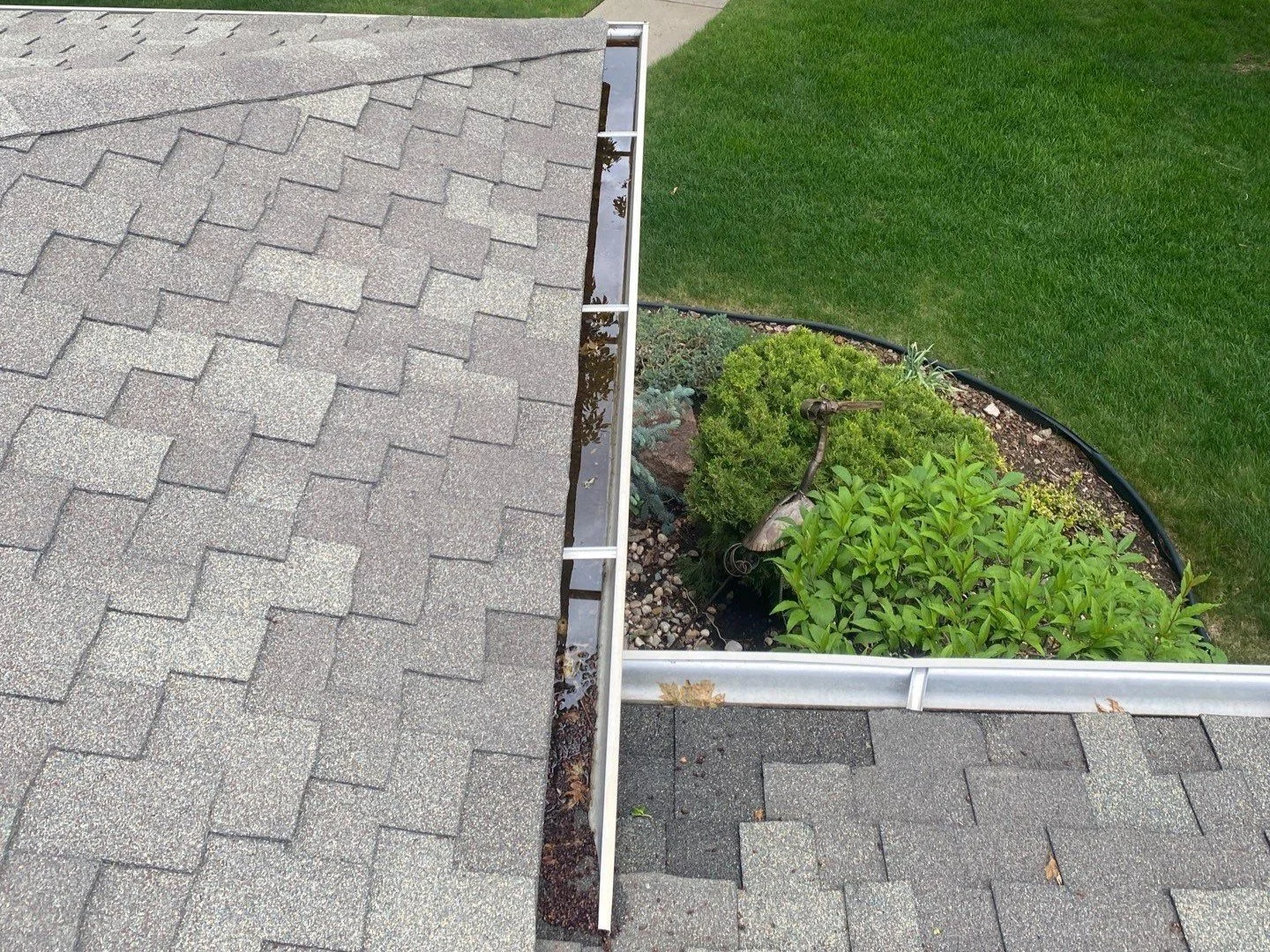 Old gutter viewed from above where two residential rooflines meet.
