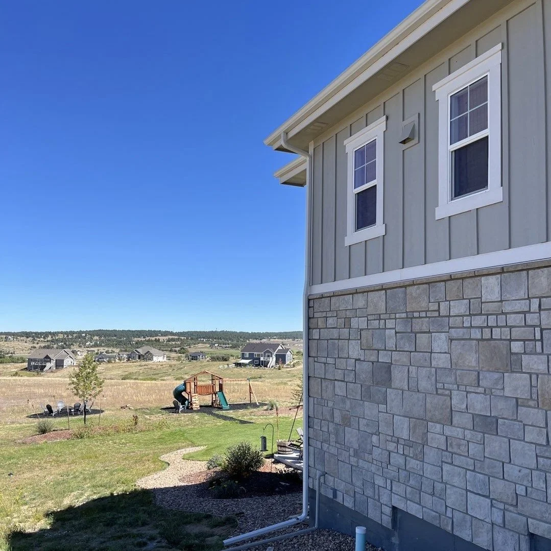 Completed seamless gutter replacement on the side of a two-story home with stone exterior accents.