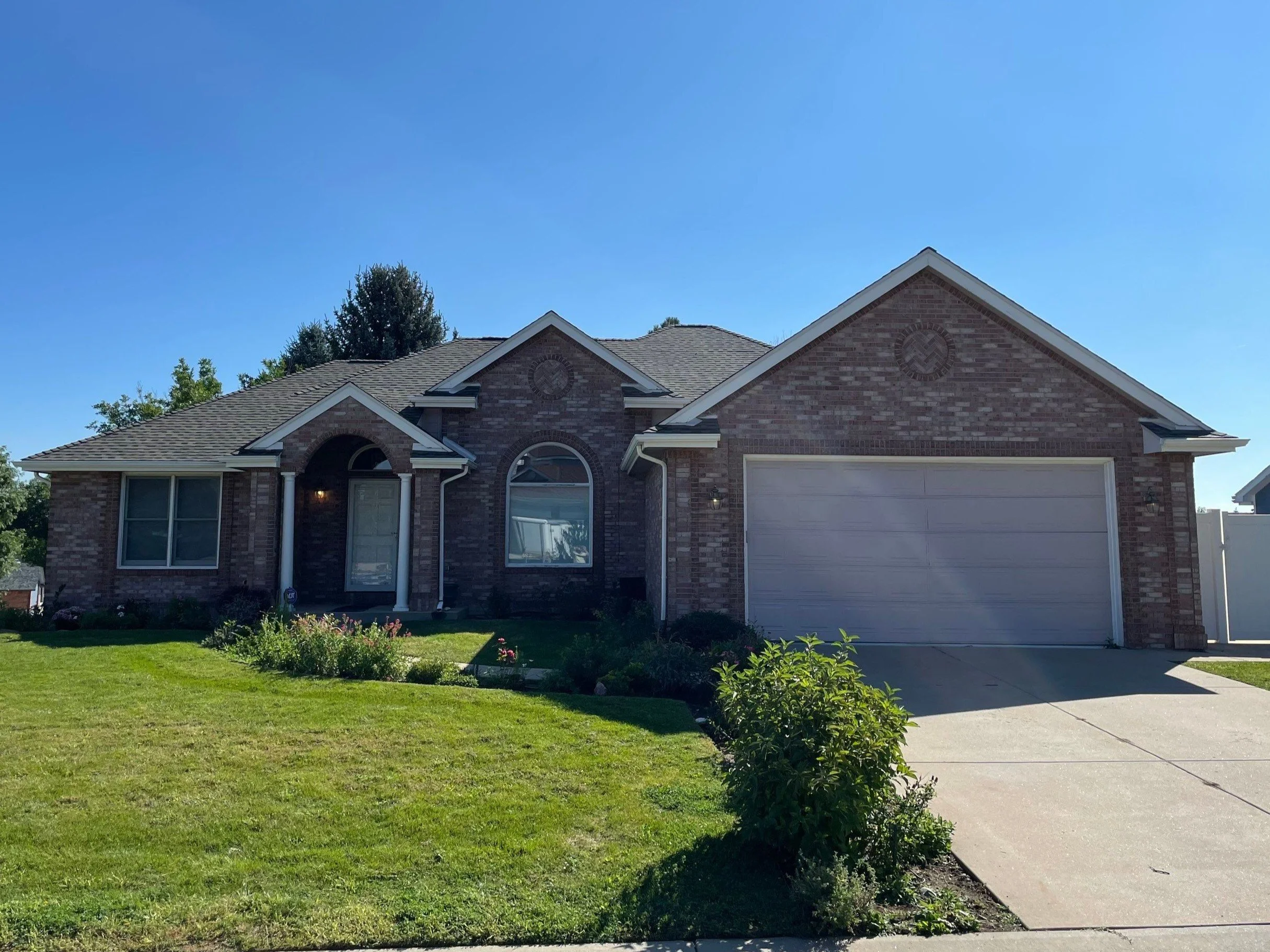 Full gutter replacement completed on a brick-front home with new gutters and downspouts installed across the main roofline.