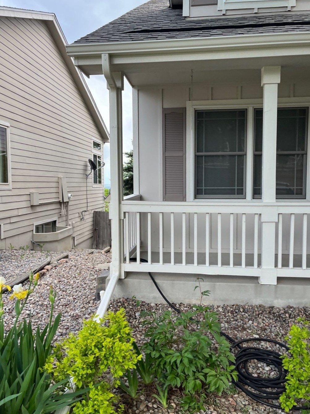 White seamless gutters and downspouts installed around the covered porch of a Lakewood home.