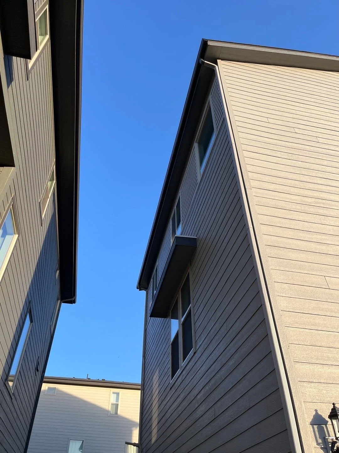 Professional seamless gutter installation along the narrow side roofline between two homes.