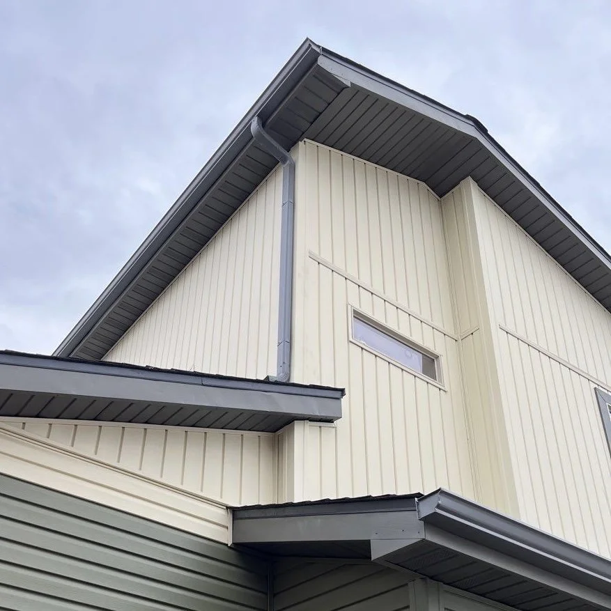 New seamless gutters and downspouts installed along the corner of a two-story home.
