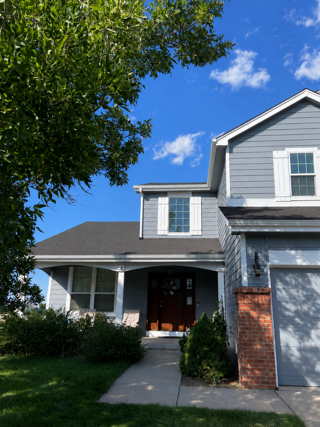 New gutters and downspouts installed across the front porch and garage rooflines of a two-story home.