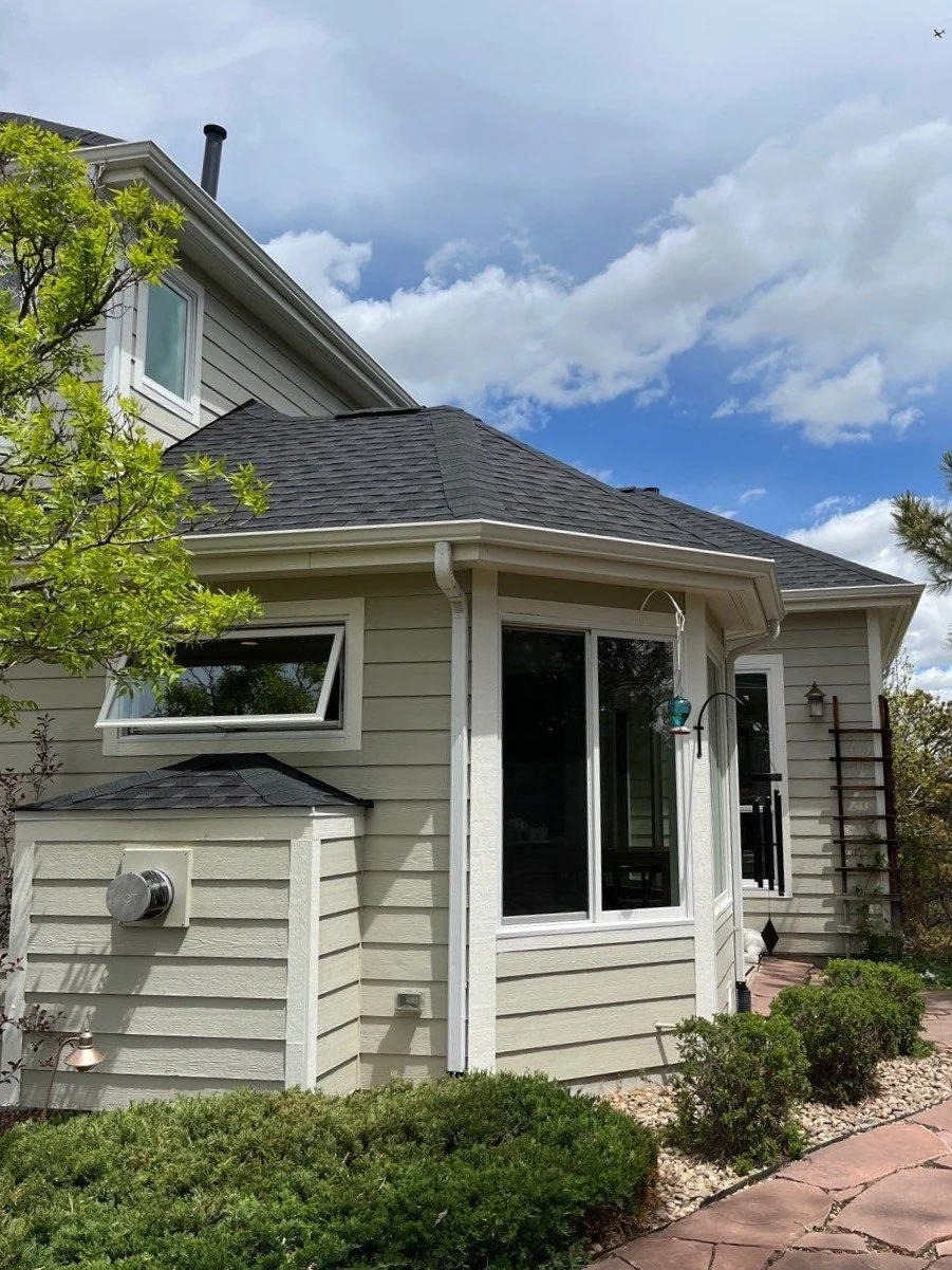 New white seamless gutter and downspout with hand-cut miters around a rear bay section in Parker, CO.