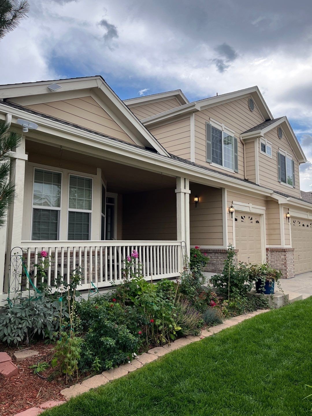 Front porch of a tan home with linen seamless gutters and downspouts.