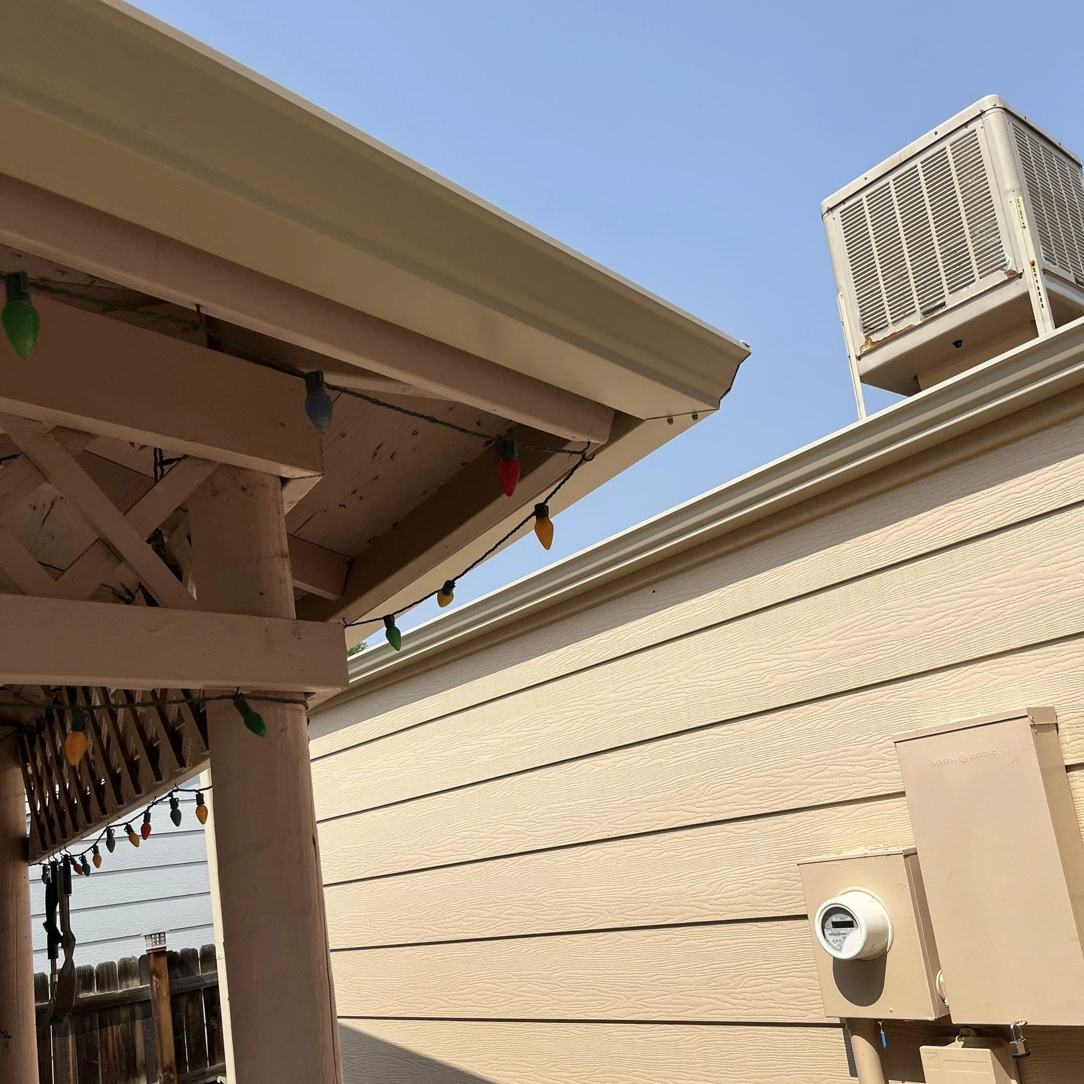 New seamless gutter and downspout system installed beside a covered patio structure.