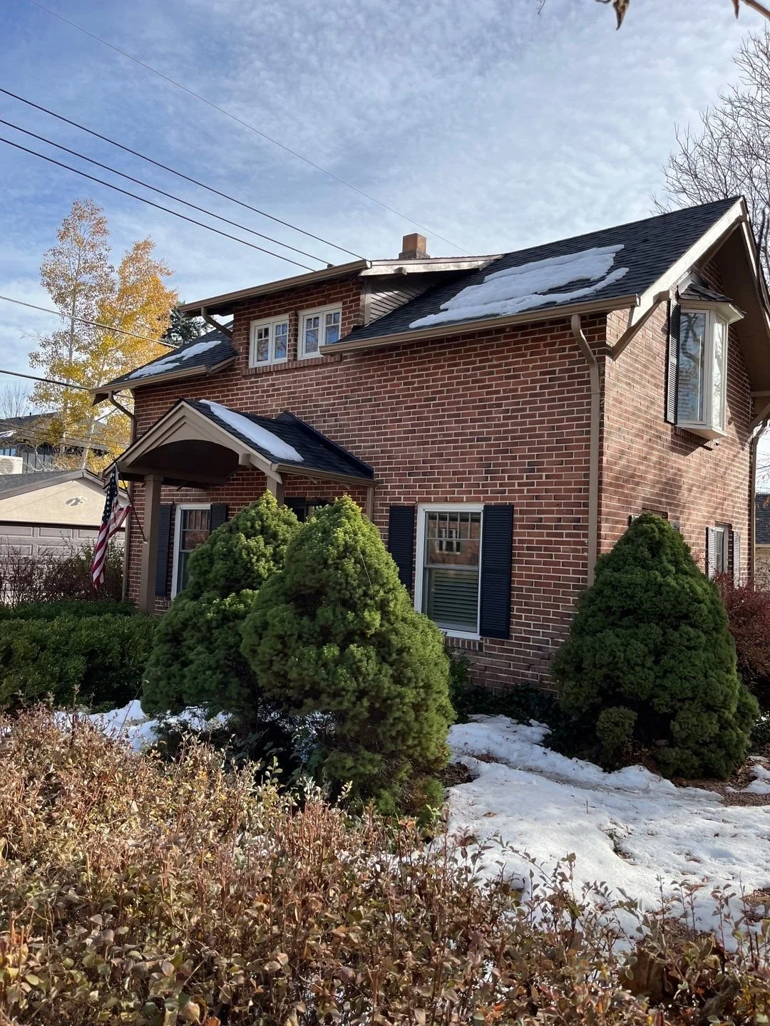 Brick home with seamless gutters and downspouts installed along the front roofline.