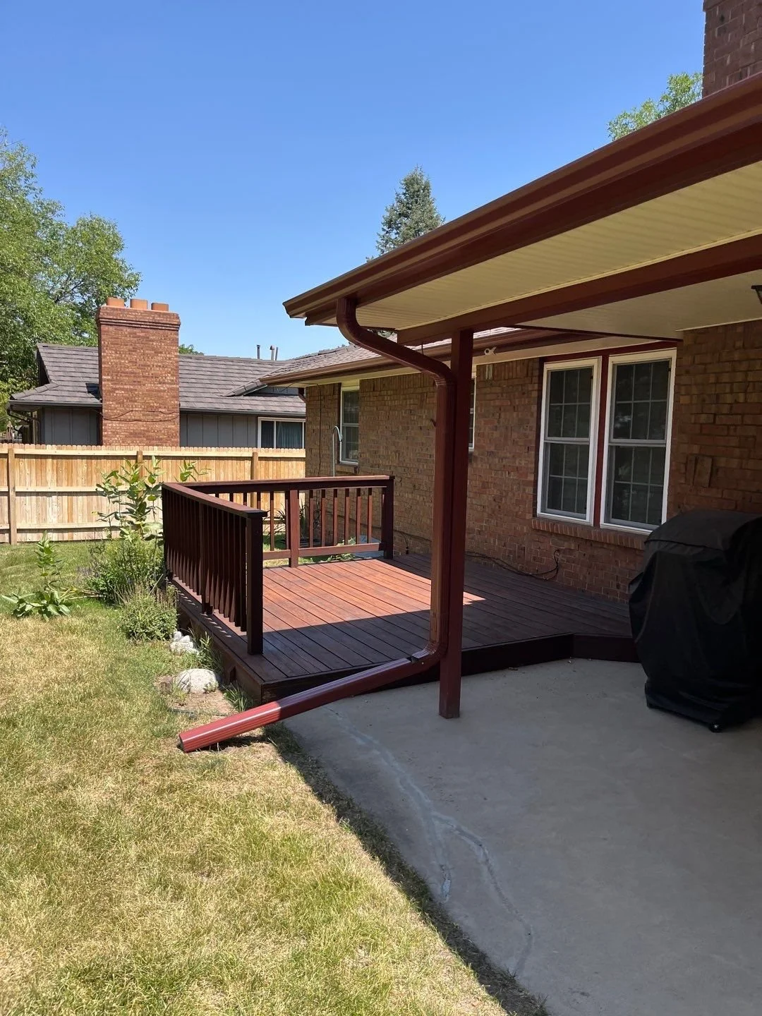 Custom gutter and downspout replacement installed around a covered backyard patio.