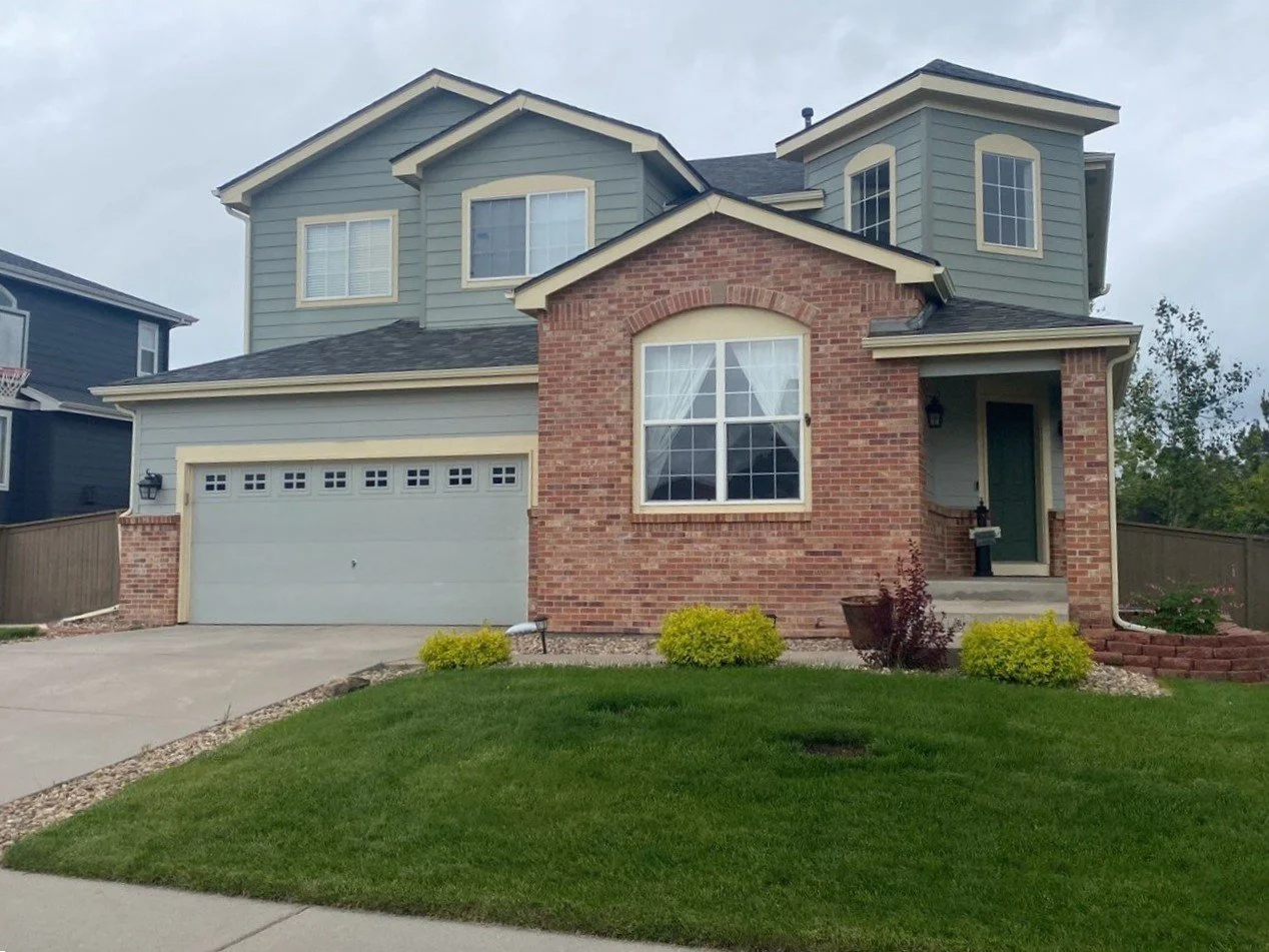 Two-story brick and siding home with sandtone seamless gutters and downspouts.