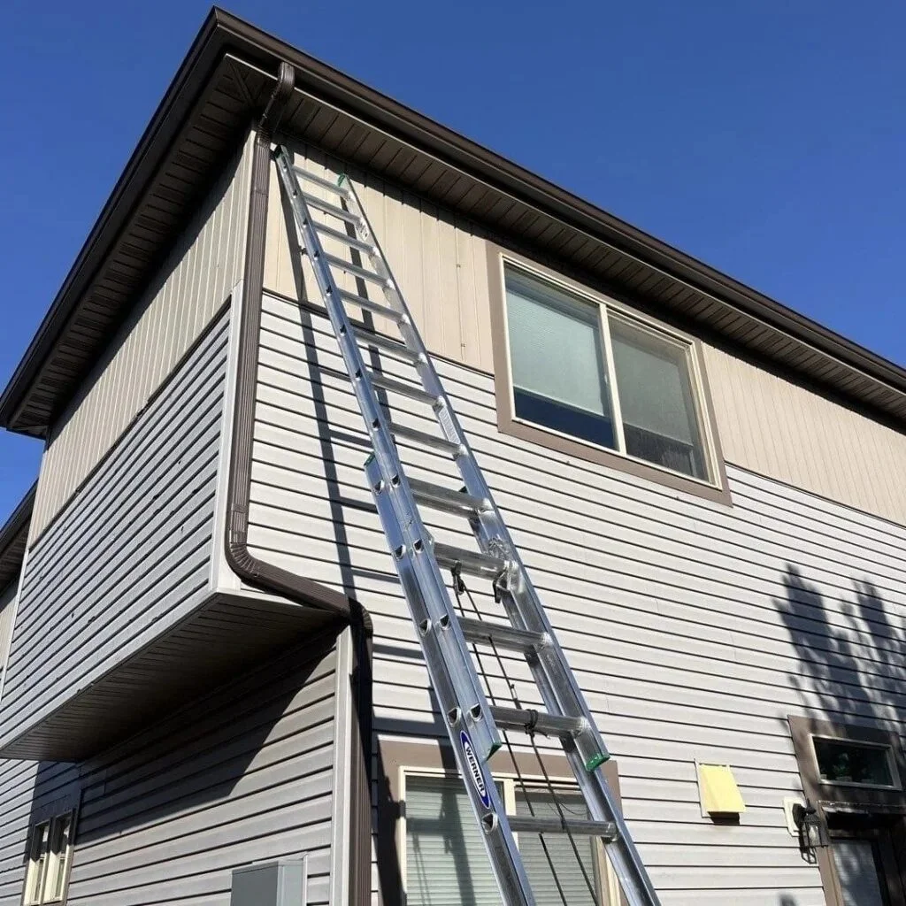 Ladder positioned for seamless gutter work along the upper roofline of a two-story home.