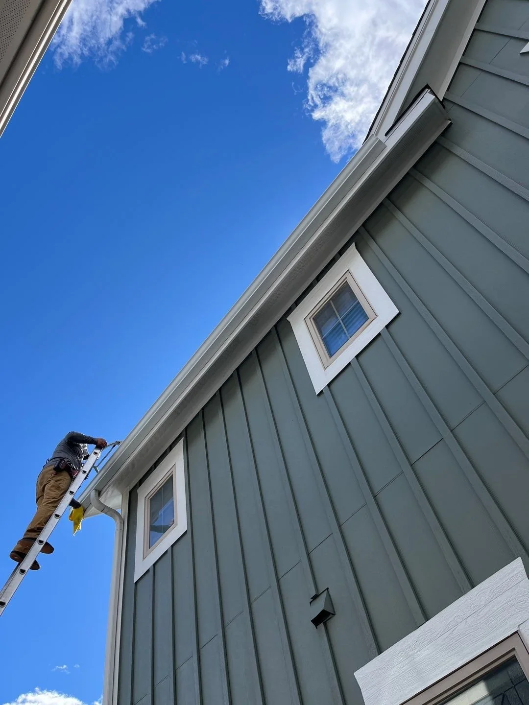 Close-up of a seamless gutter installed along the upper roofline of a siding home.