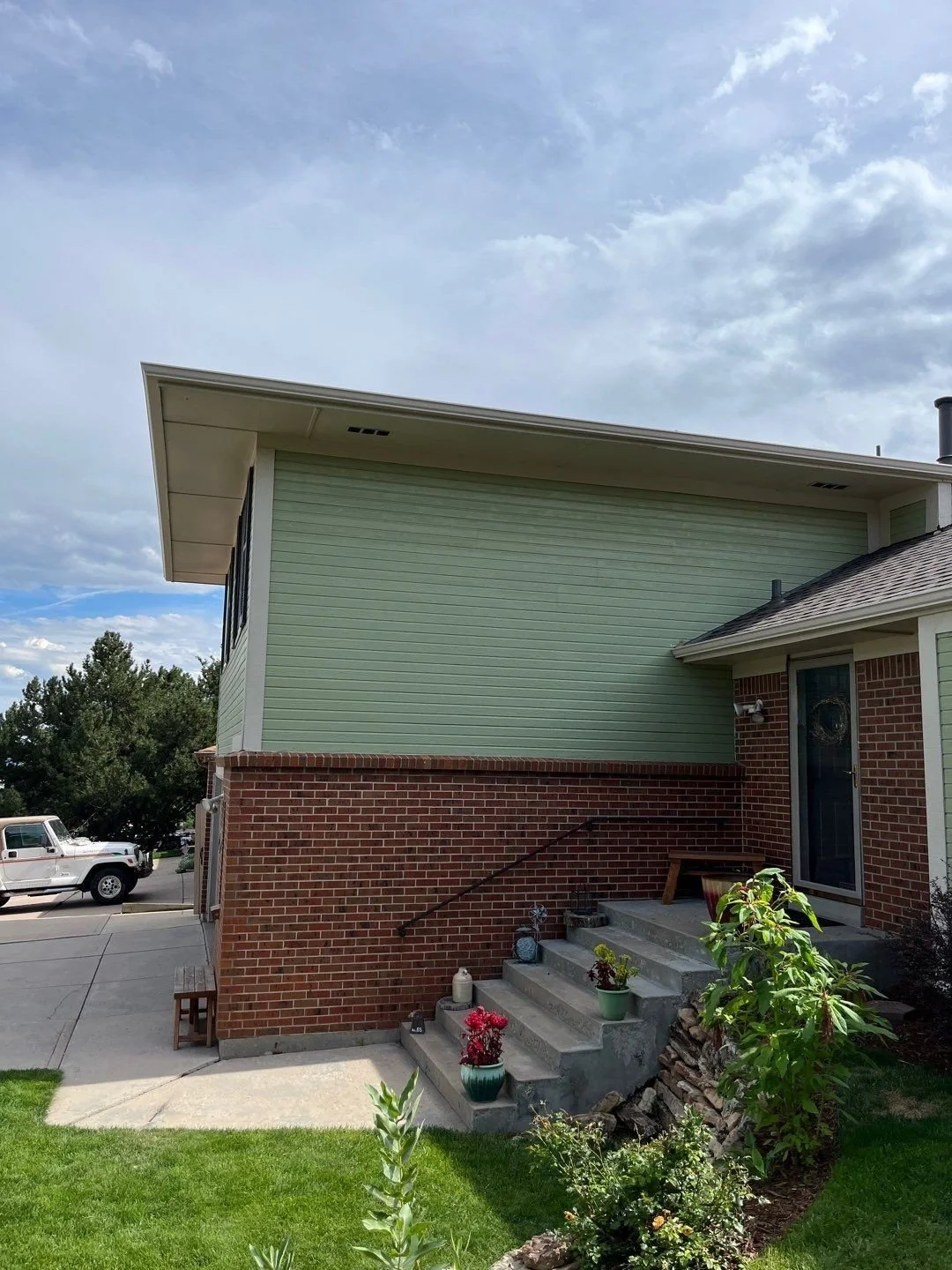 Seamless gutter installation completed along the front roofline of a brick and siding home.