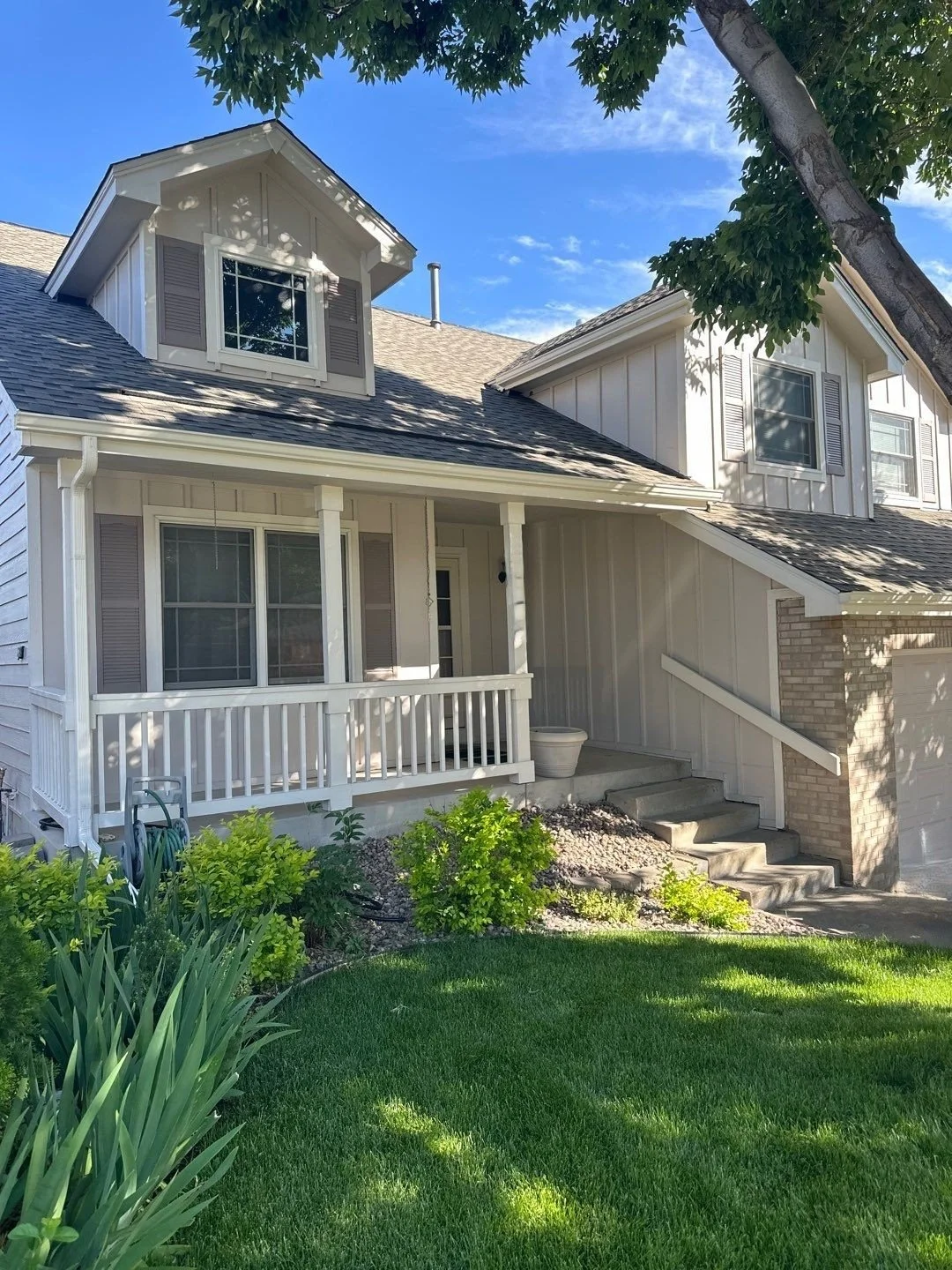 New seamless gutters and downspouts fitted around the front porch and upper rooflines of a two-story home.