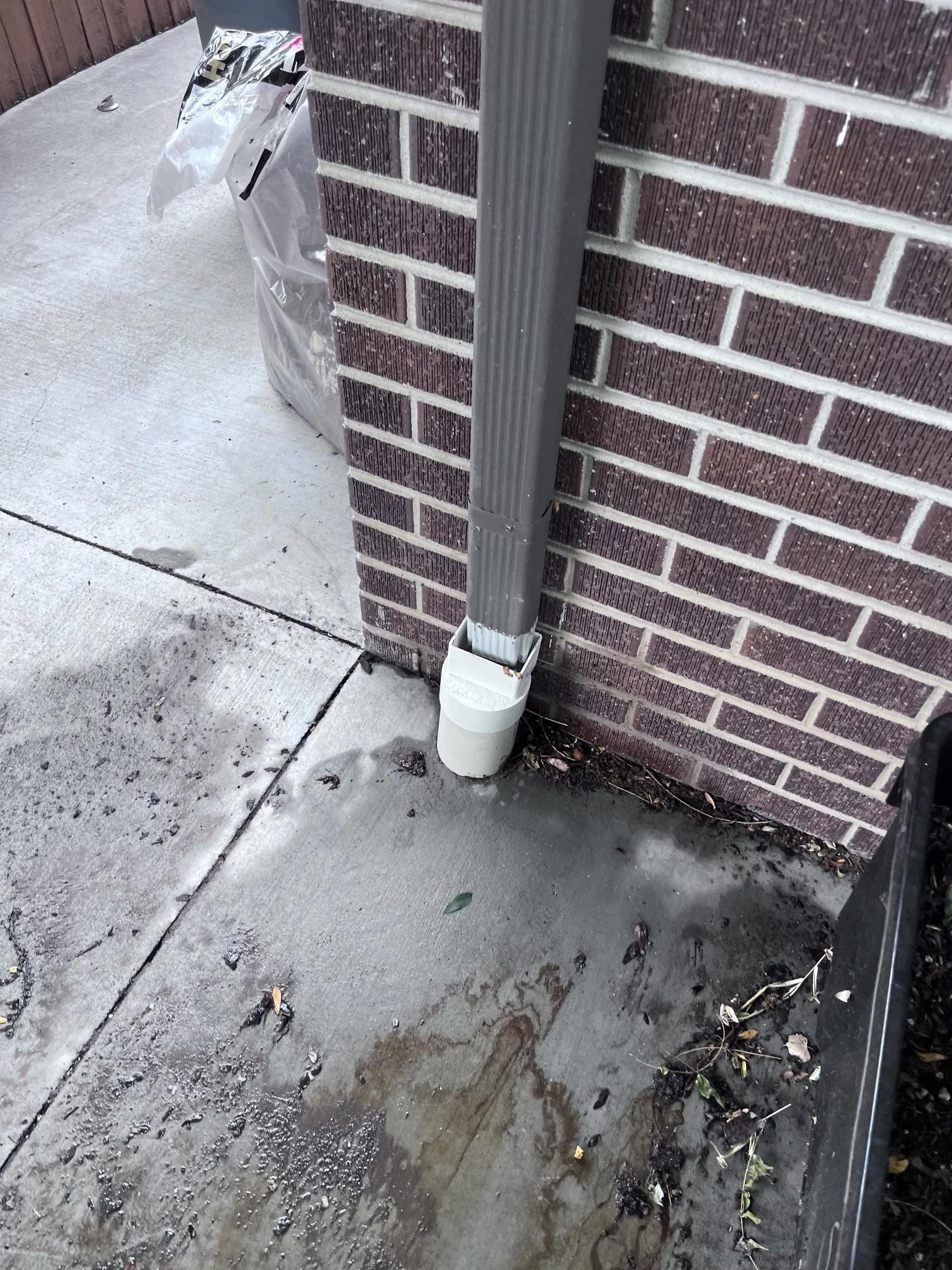 A 2×3-inch downspout reconnected to the underground drain after gutter cleaning was completed.