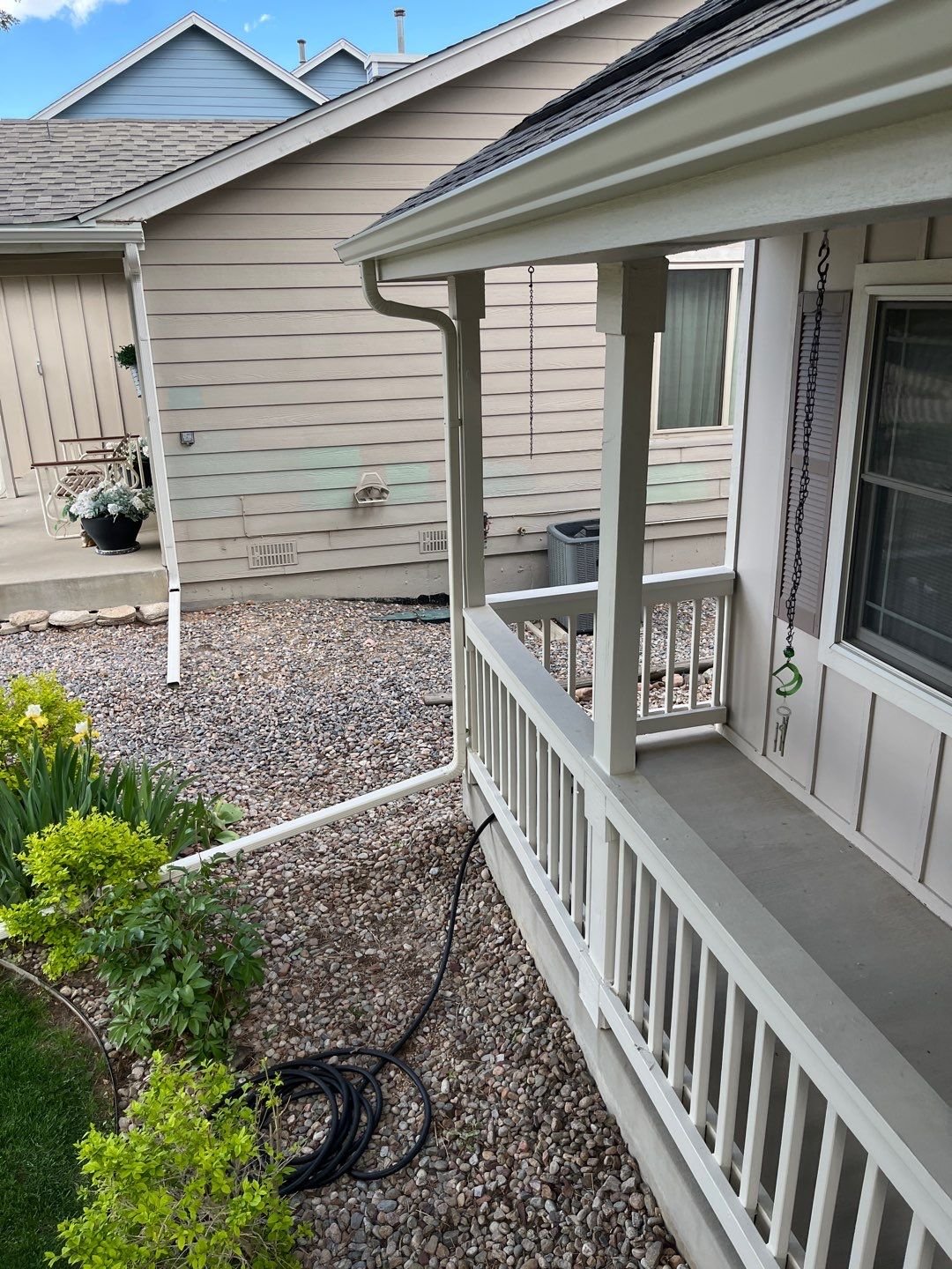 Linen-colored seamless gutter and 2×3-inch downspout installed along the front porch of a Green Mountain home in Lakewood.