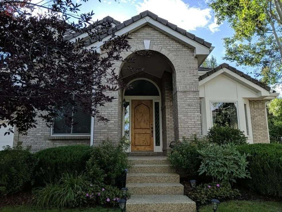 Custom seamless gutter replacement completed around the front entry and upper roofline of a stucco and brick home.