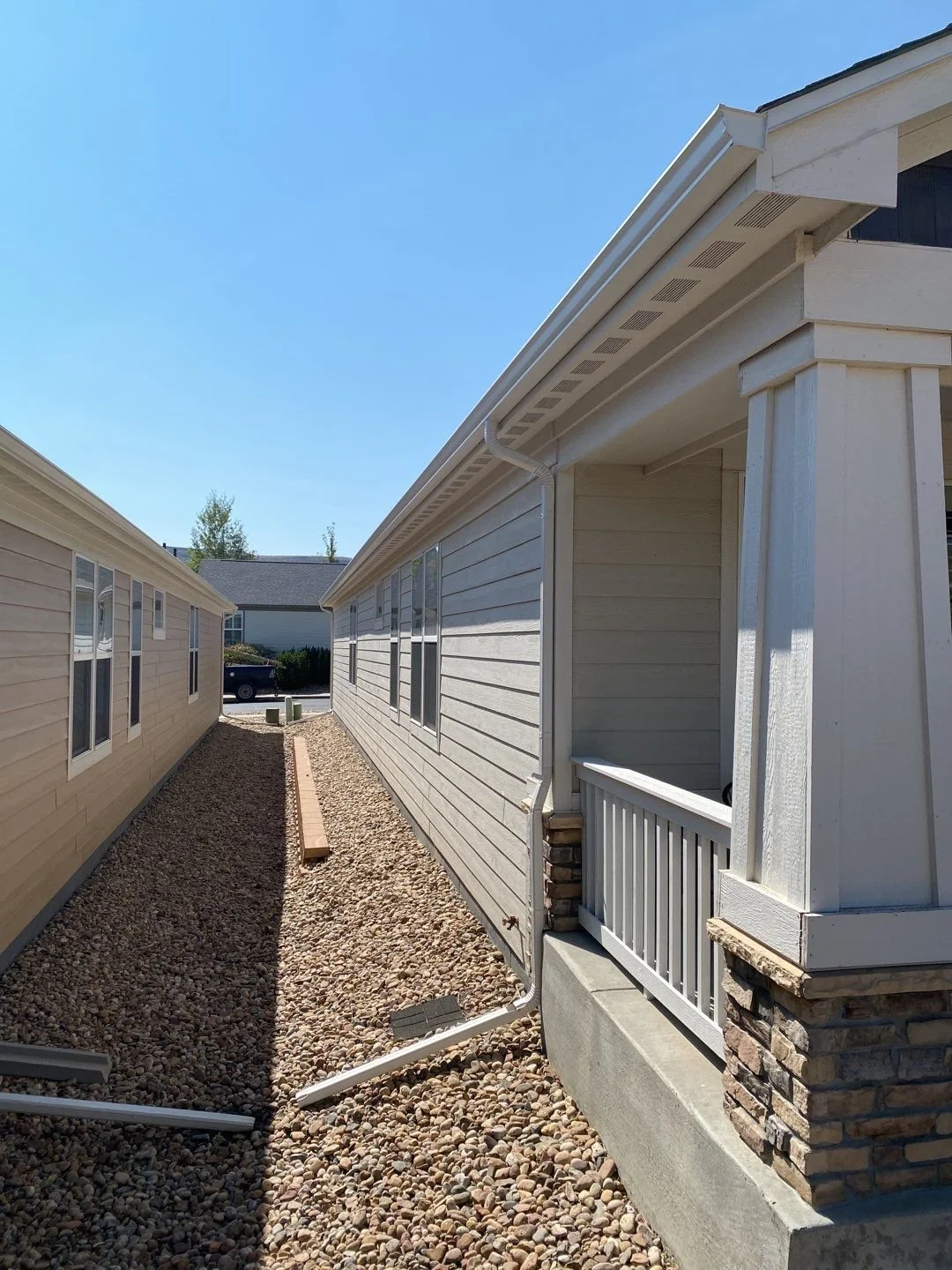 New seamless gutters and downspouts installed along the side of a residential home.