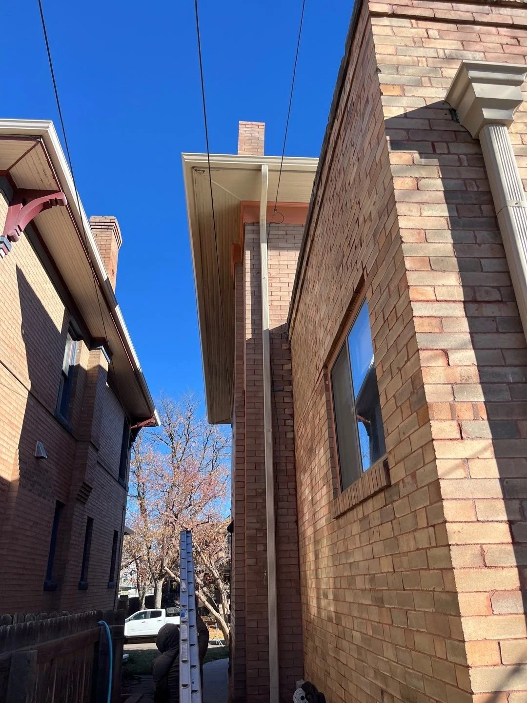 Close-up of a seamless gutter and downspout system between neighboring homes.