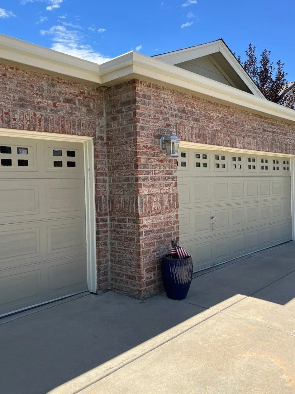 New gutters and downspouts were installed across the brick garage roofline.