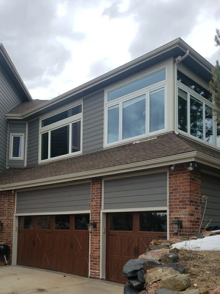 Complete gutter system installed above the garage and upper-story windows of a brick home.