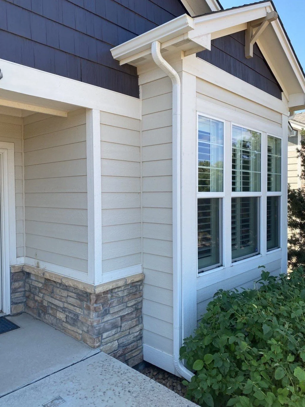 Custom gutter replacement around a projecting window section with stone and siding details.
