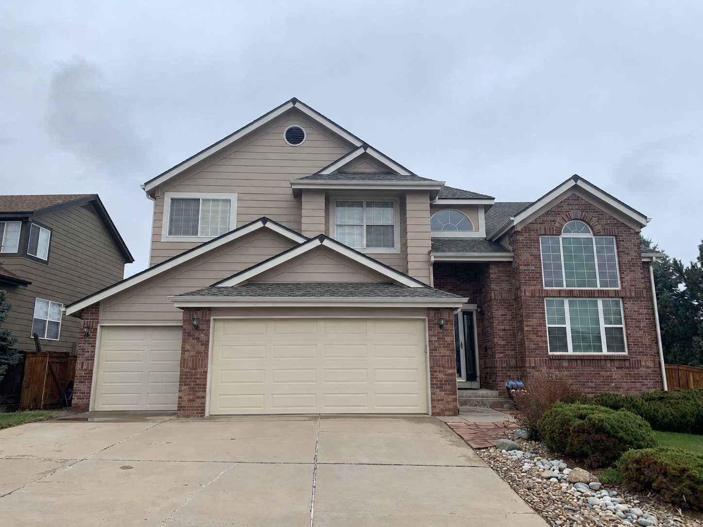 Complete gutter and downspout replacement added to a two-story home with brick accents and an attached garage.