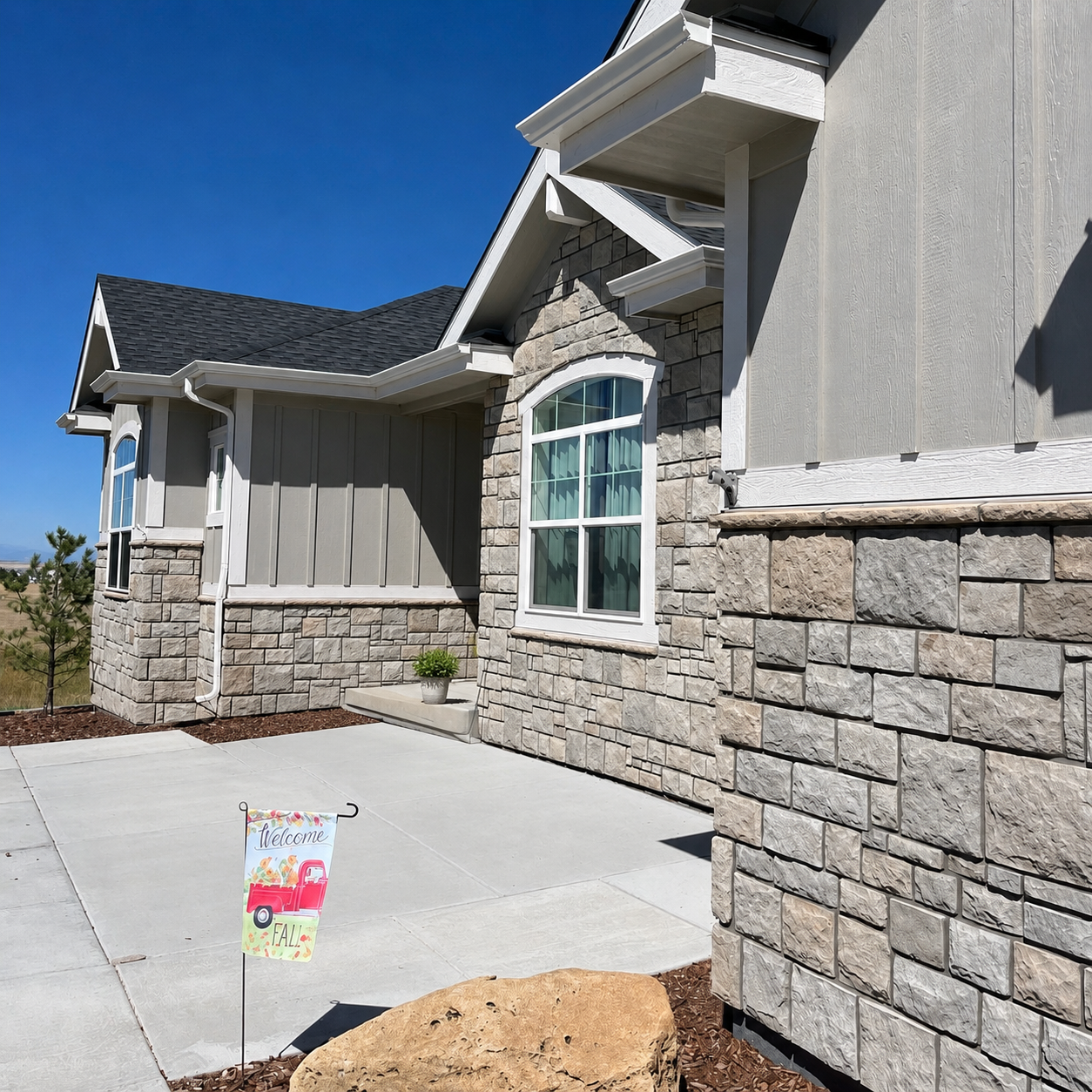 Front entry with seamless gutters and downspouts installed on a home with stone accents.