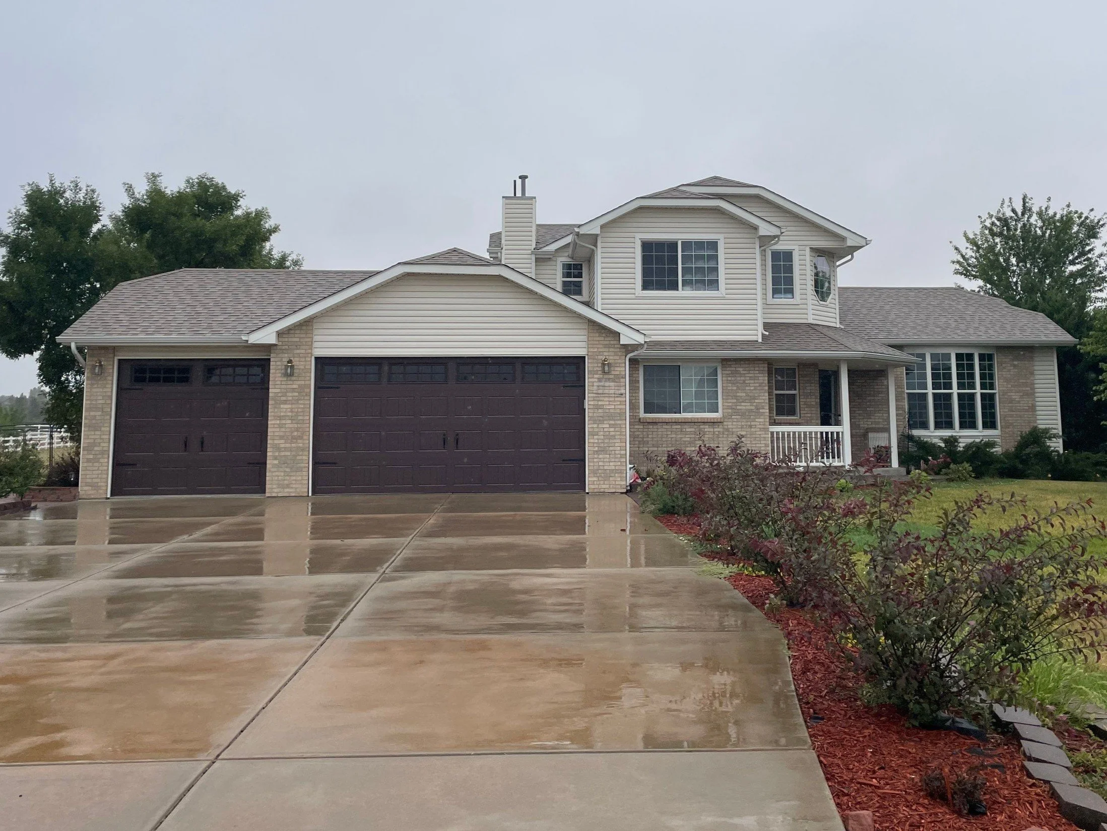 Two-story home with an attached garage, landscaped front yard, and seamless gutters in the Denver Metro area.