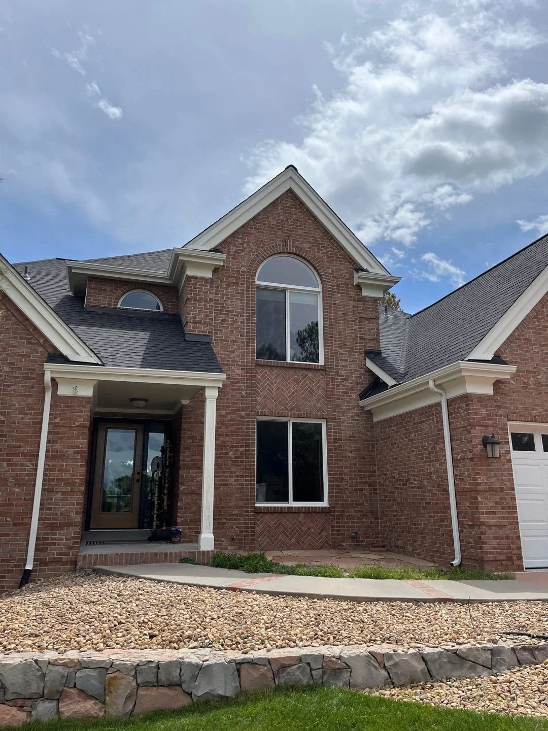 Completed white seamless gutter and downspout installation on the brick front exterior of a Parker, CO home.