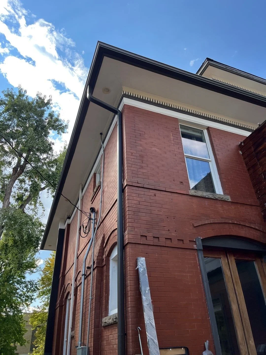 Seamless gutter and downspout installation on the rear corner of a brick home.