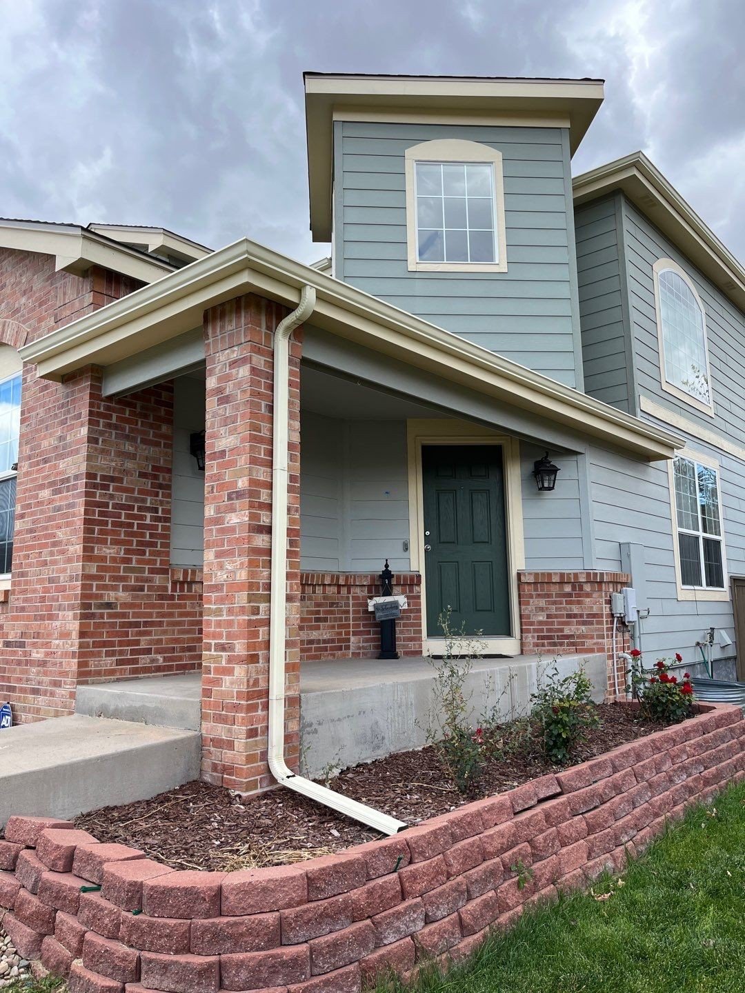 Almond downspout installed on a brick and siding home in the Denver Metro area.