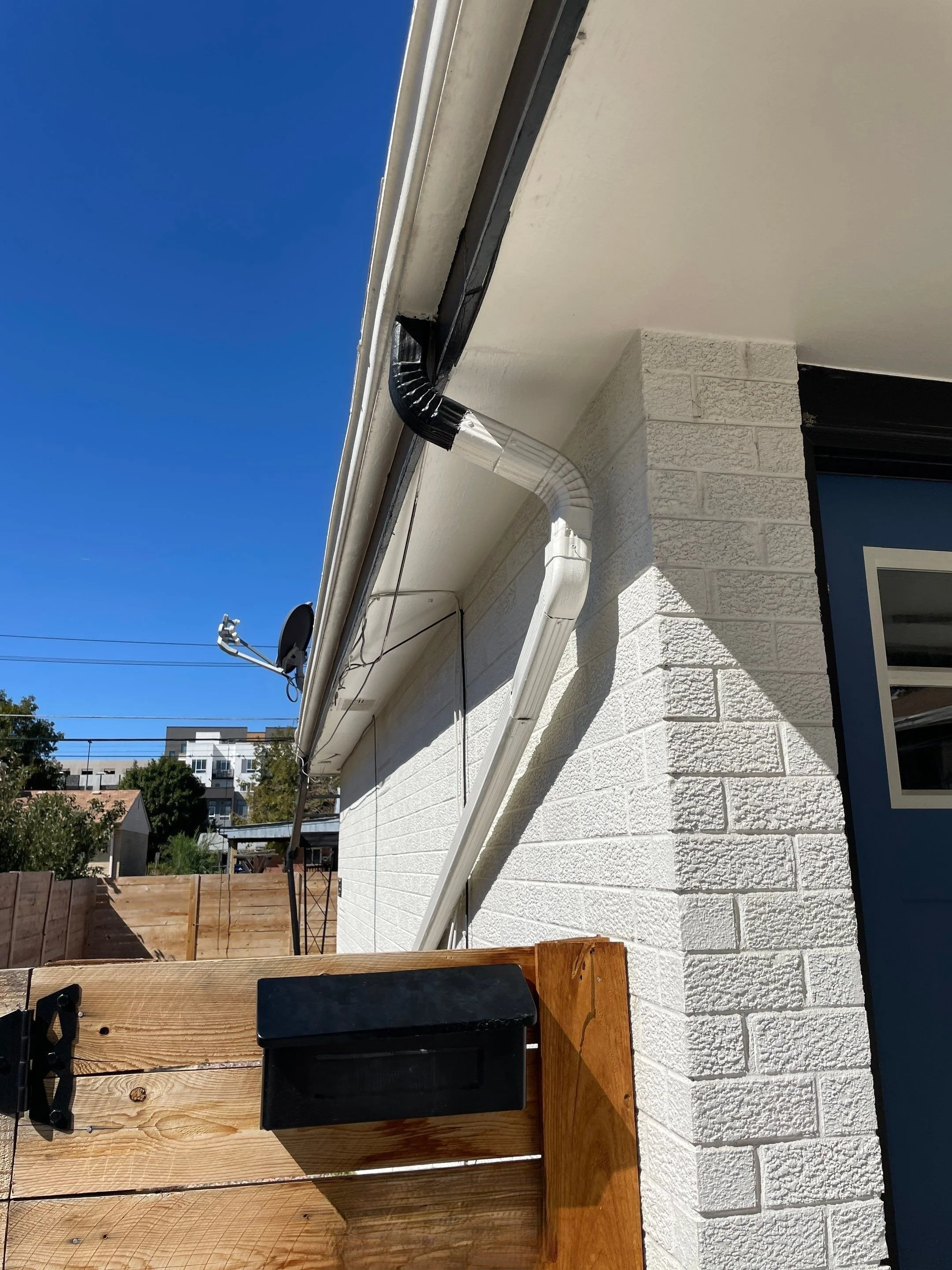 Old sagging white downspout in a poor location before gutter replacement on a home in Aurora, CO.