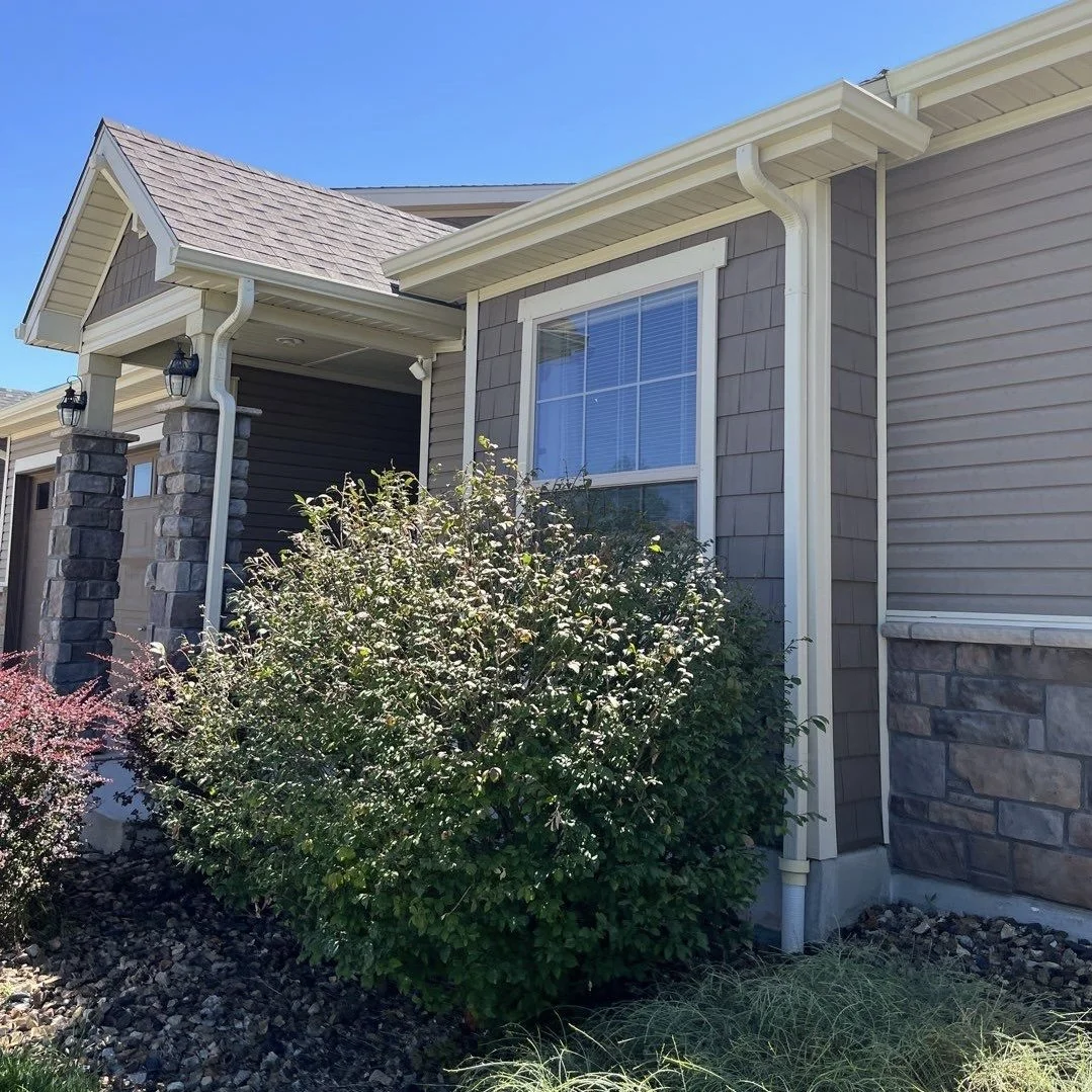 Residential gutter replacement with new seamless gutters and downspouts installed along the front roofline.