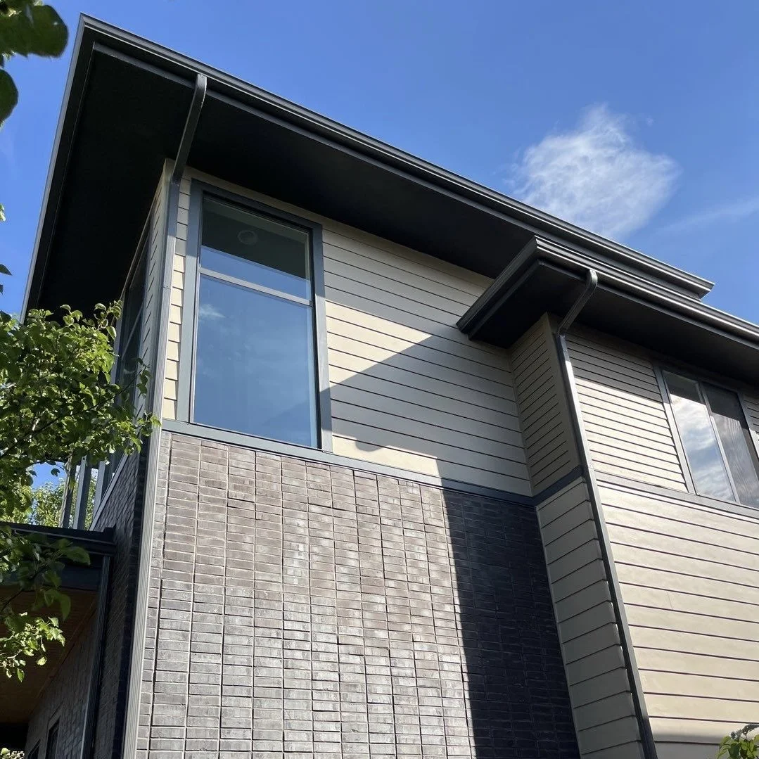 Professional gutter replacement with new seamless gutters and downspouts on a modern two-story home.