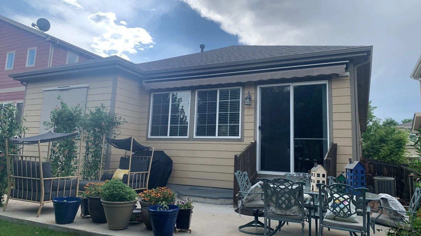 New seamless gutters and downspouts installed above a residential patio and window area.