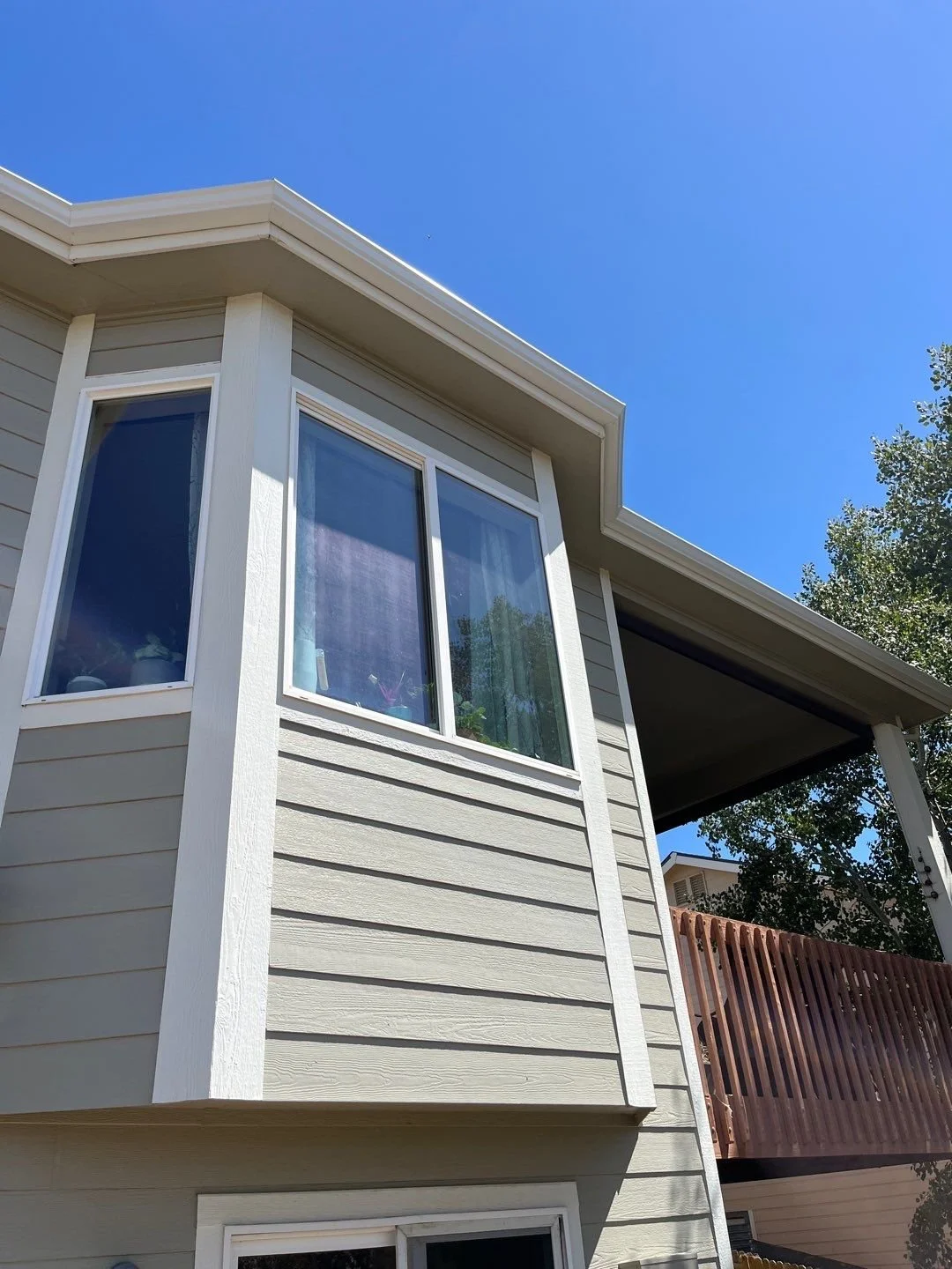 Custom seamless gutters fitted around a projecting upper-story bay window section.