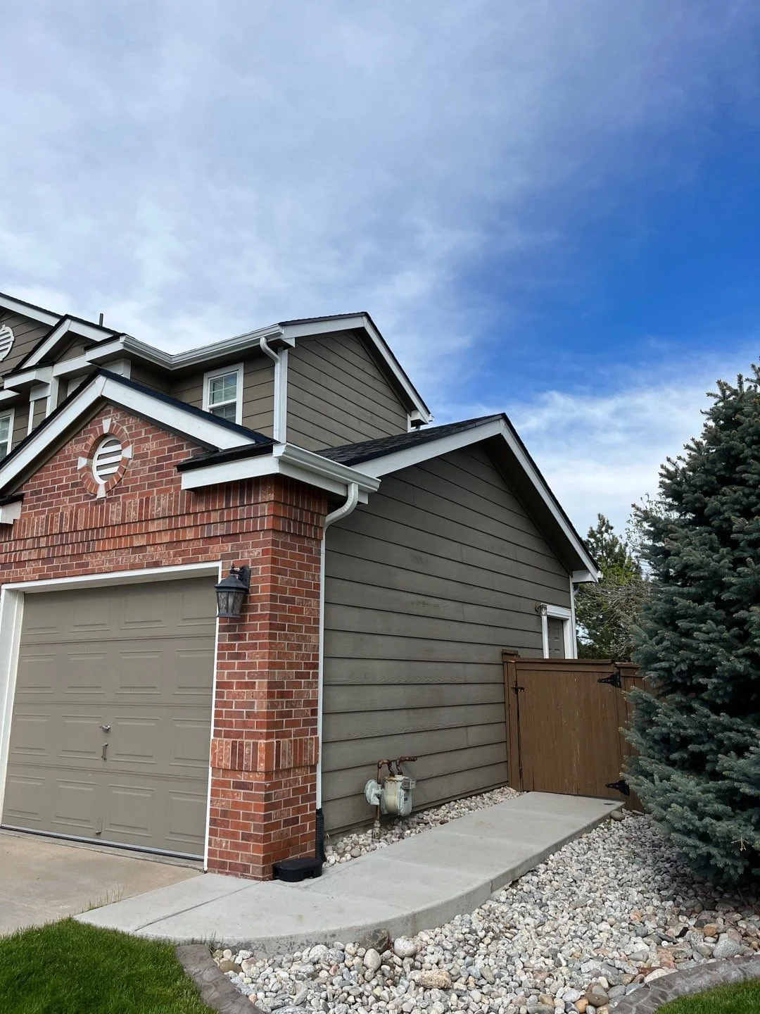 Gutter and downspout replacement completed along the brick garage and side roof edge.
